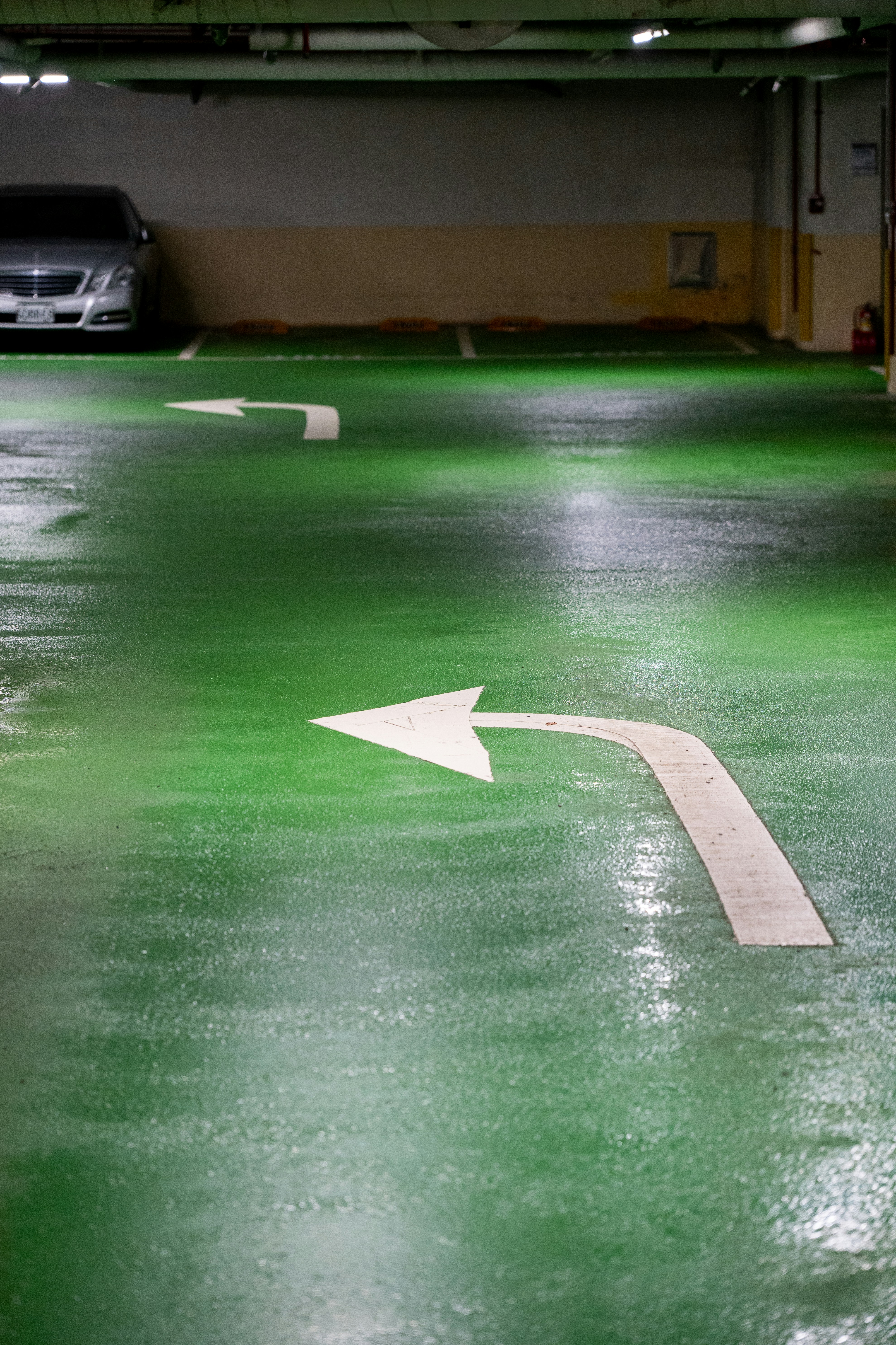 Grüner Parkhausboden mit weißen Pfeilen.
