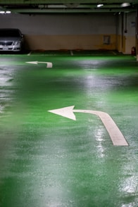 Green parking garage floor with white arrows.