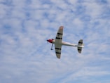 A small propeller airplane flies in a cloudy sky.