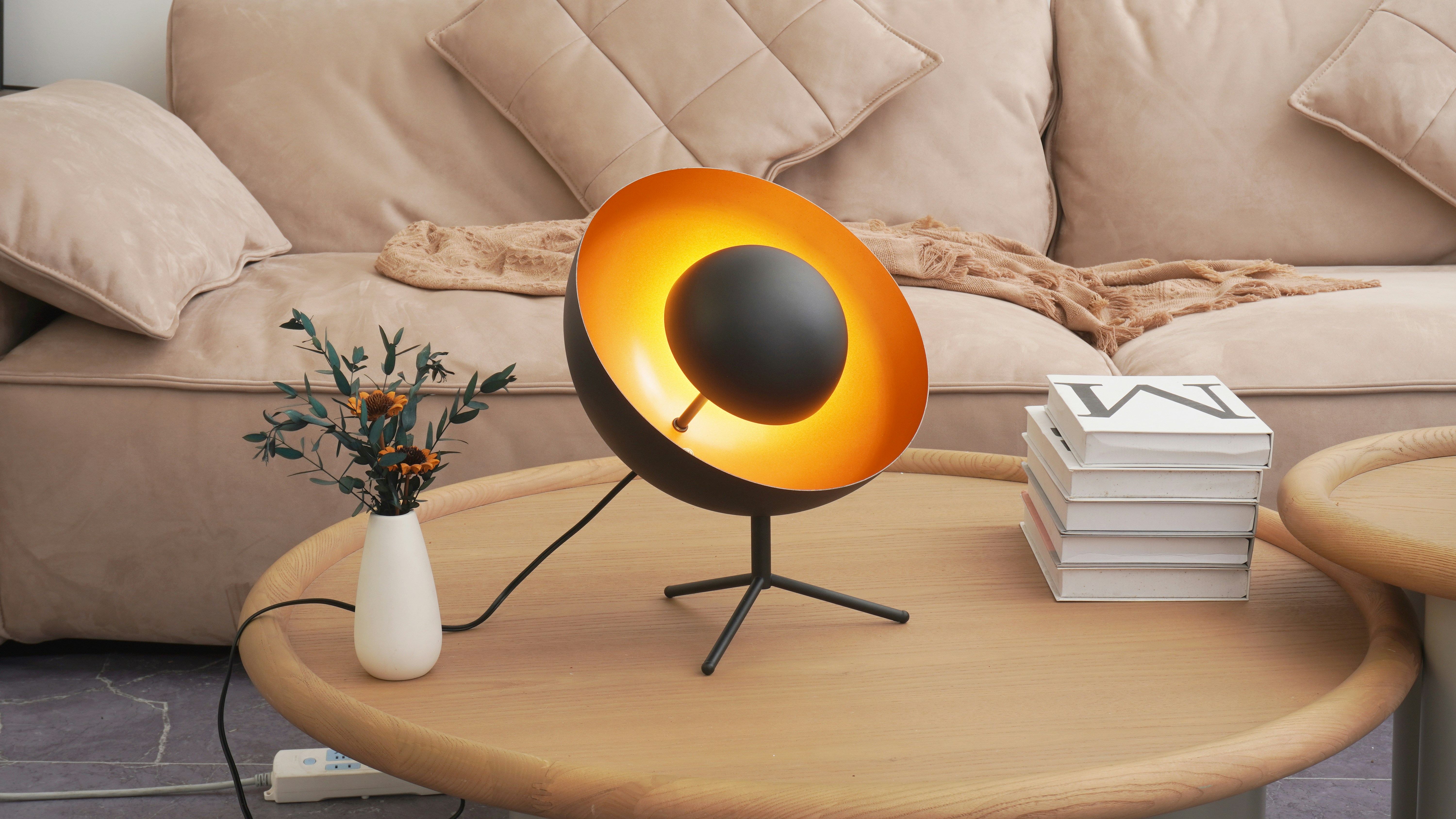 modern apartment living room with a sculptural orange gold bowl lamp on a round coffee table and beige sofa