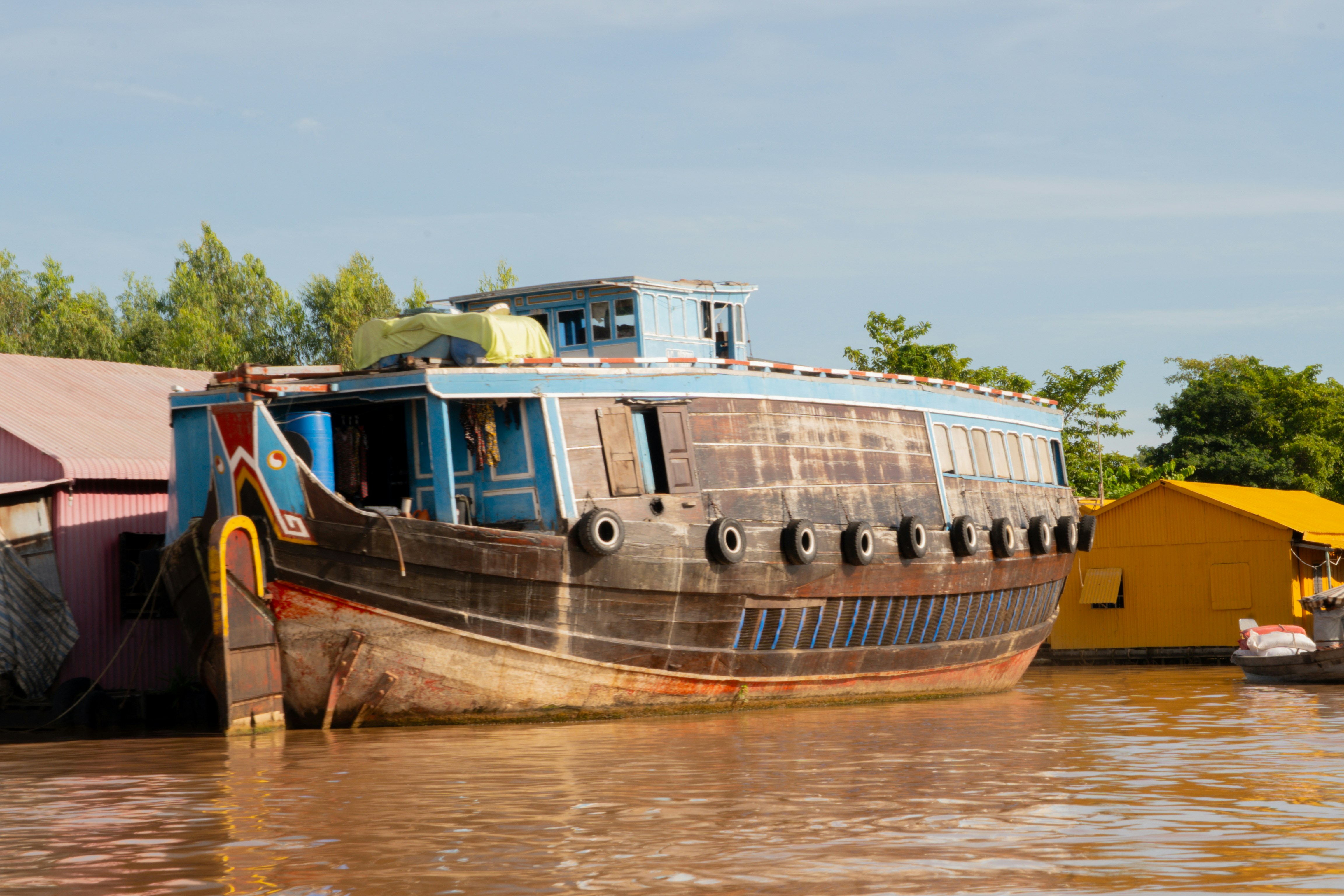 Old wooden boat docked near colorful buildings on water.