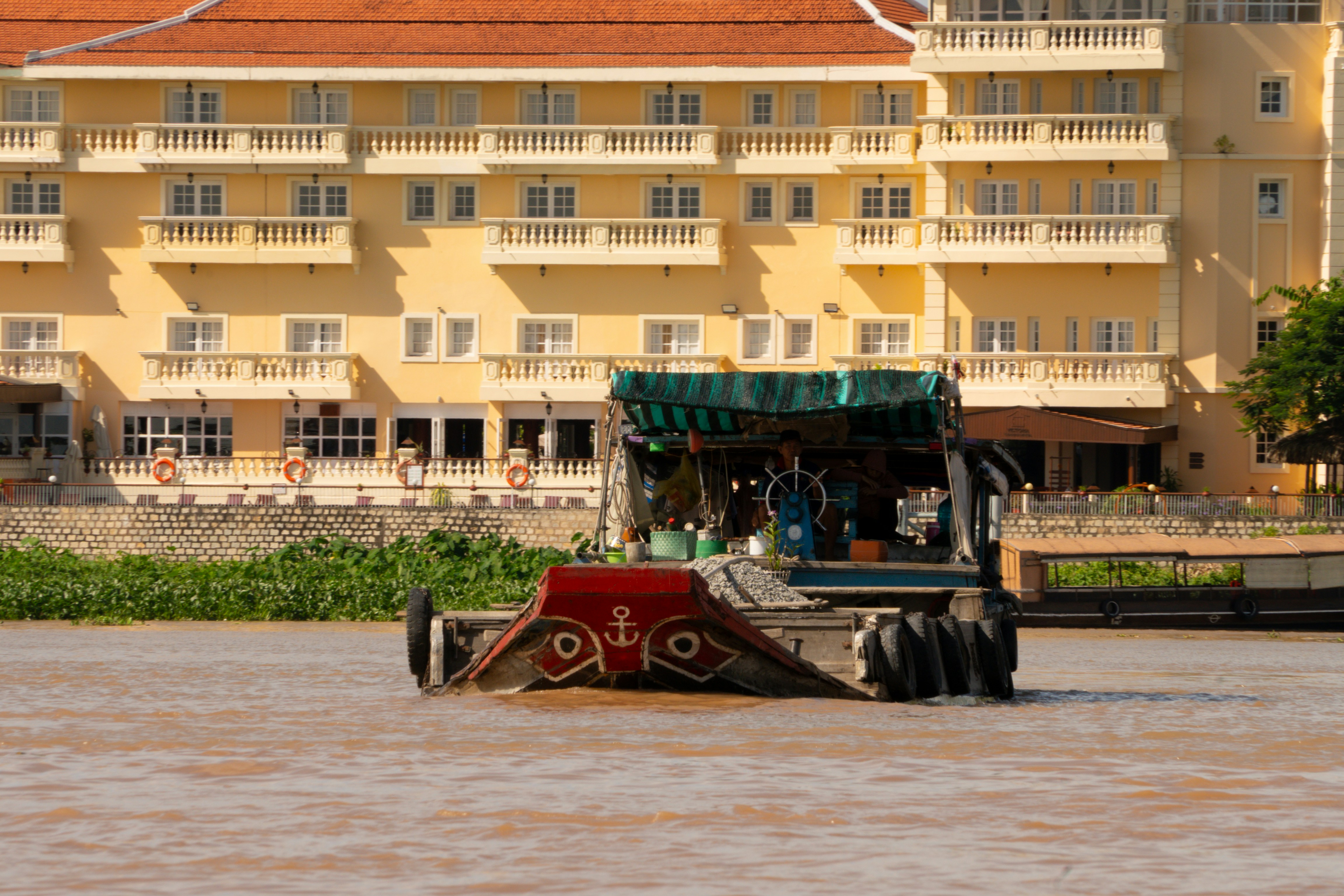 A boat on a muddy river with a building behind.