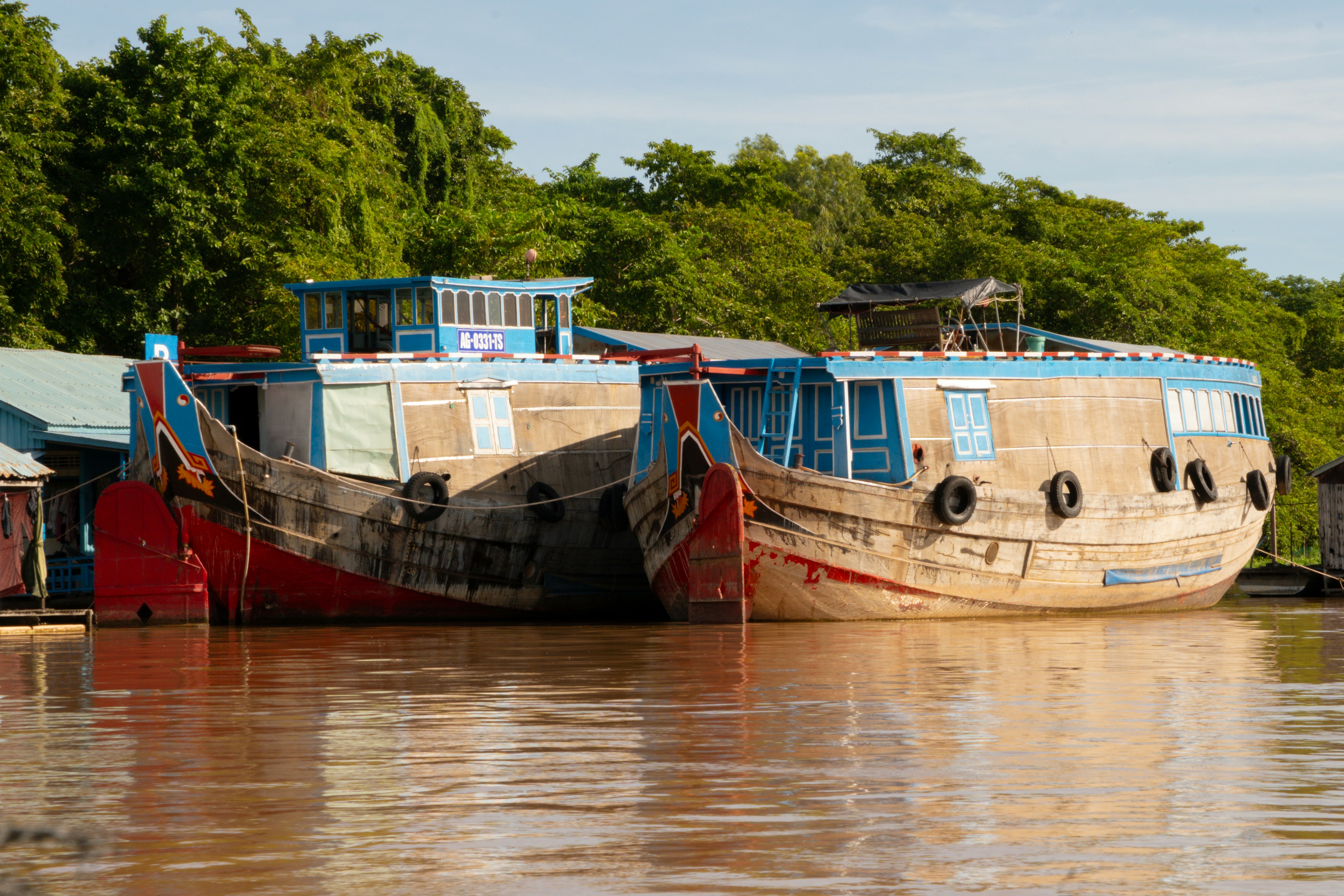 Two old wooden boats docked on a river.