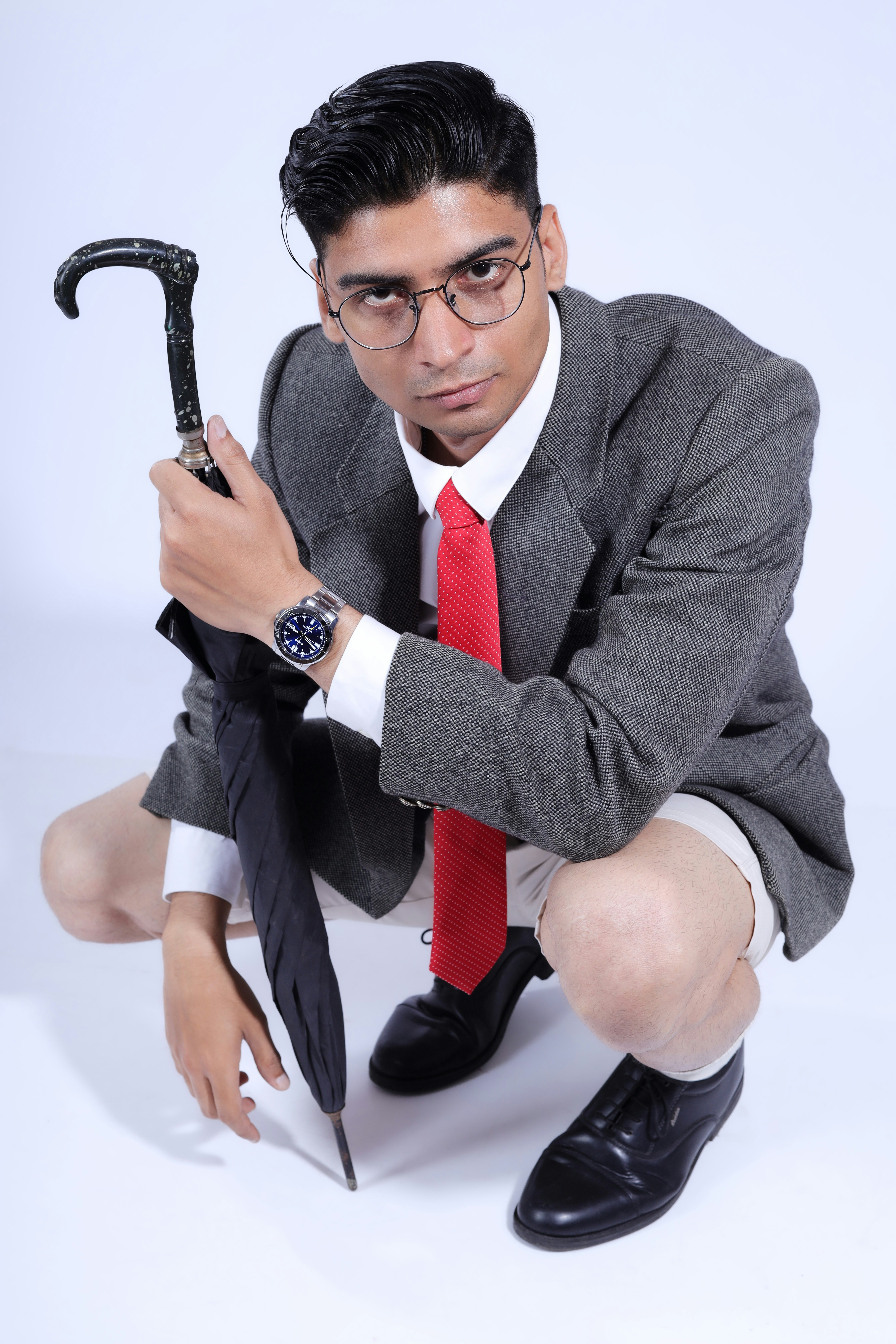 Man in suit and tie with umbrella crouching