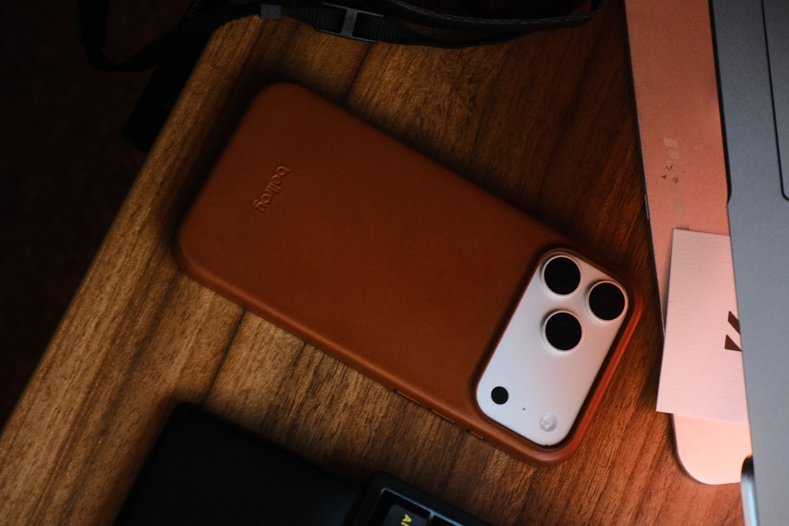 Brown protective smartphone case beside a laptop on a wooden desk