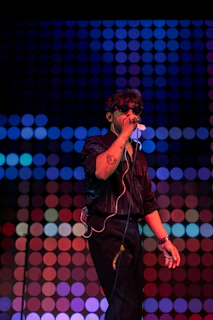 Man singing into microphone with colorful lights