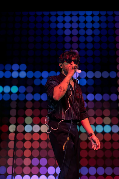 Man singing into microphone with colorful lights