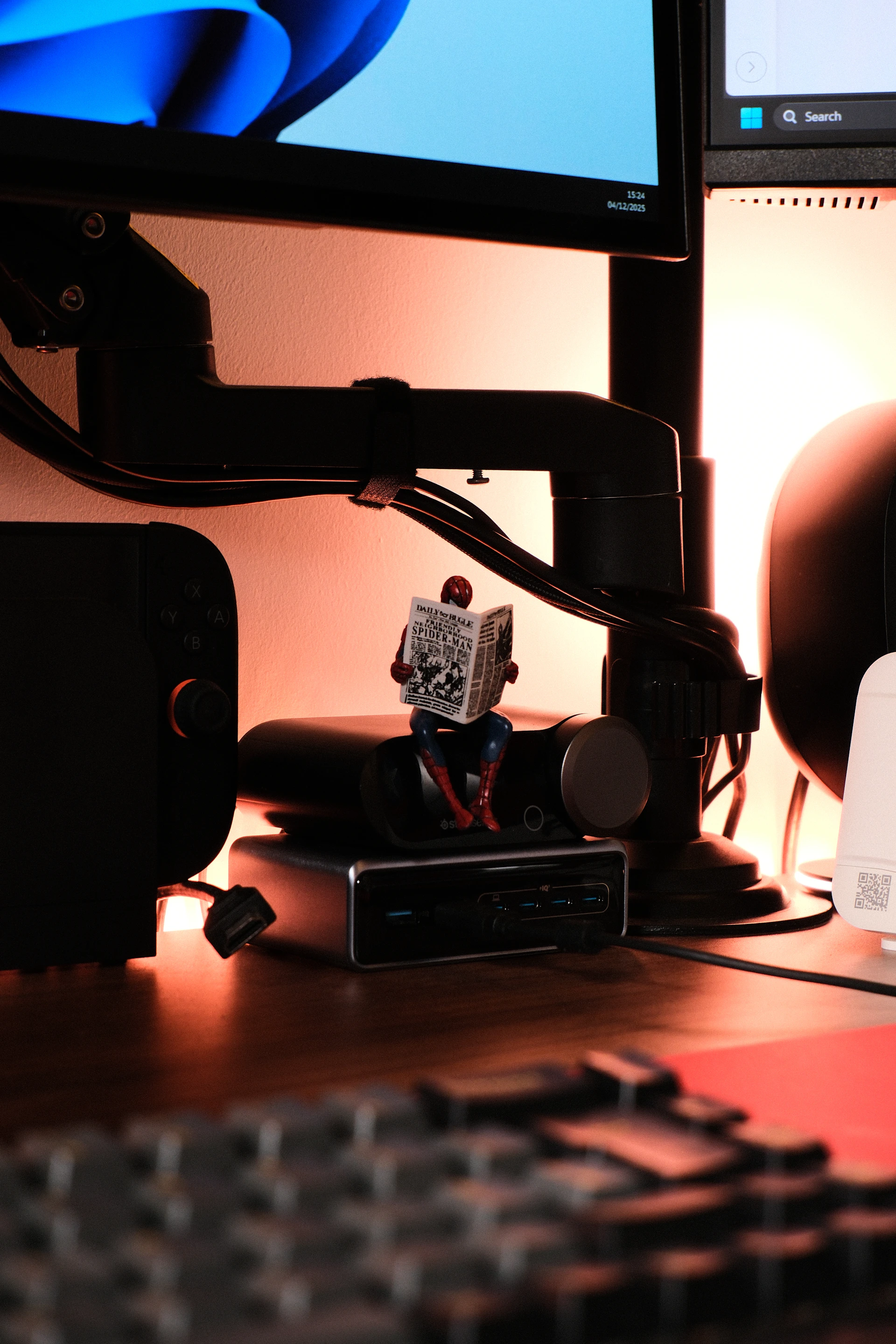 Spider-man figurine reading newspaper on computer equipment.