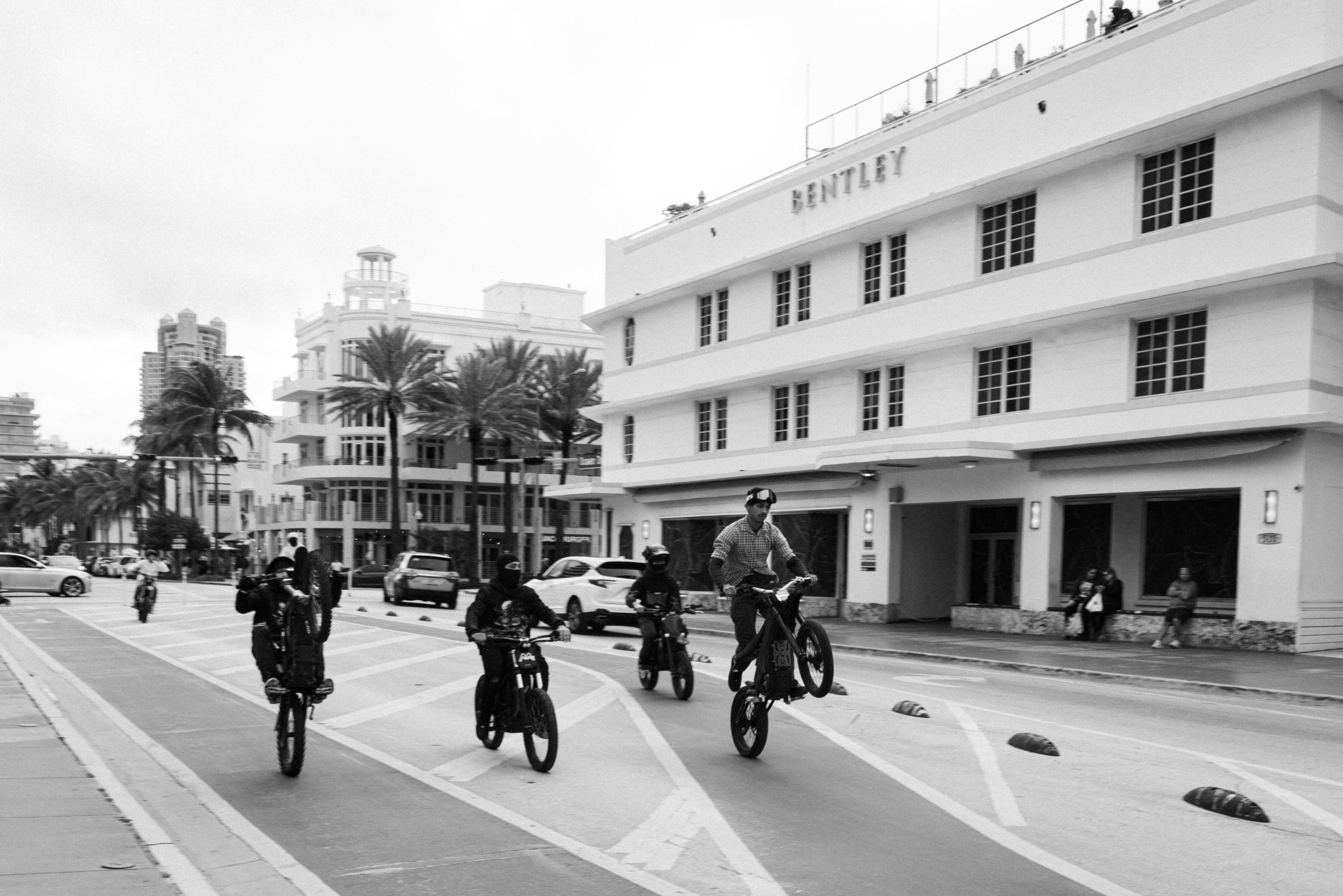 People riding bicycles on a street with buildings.