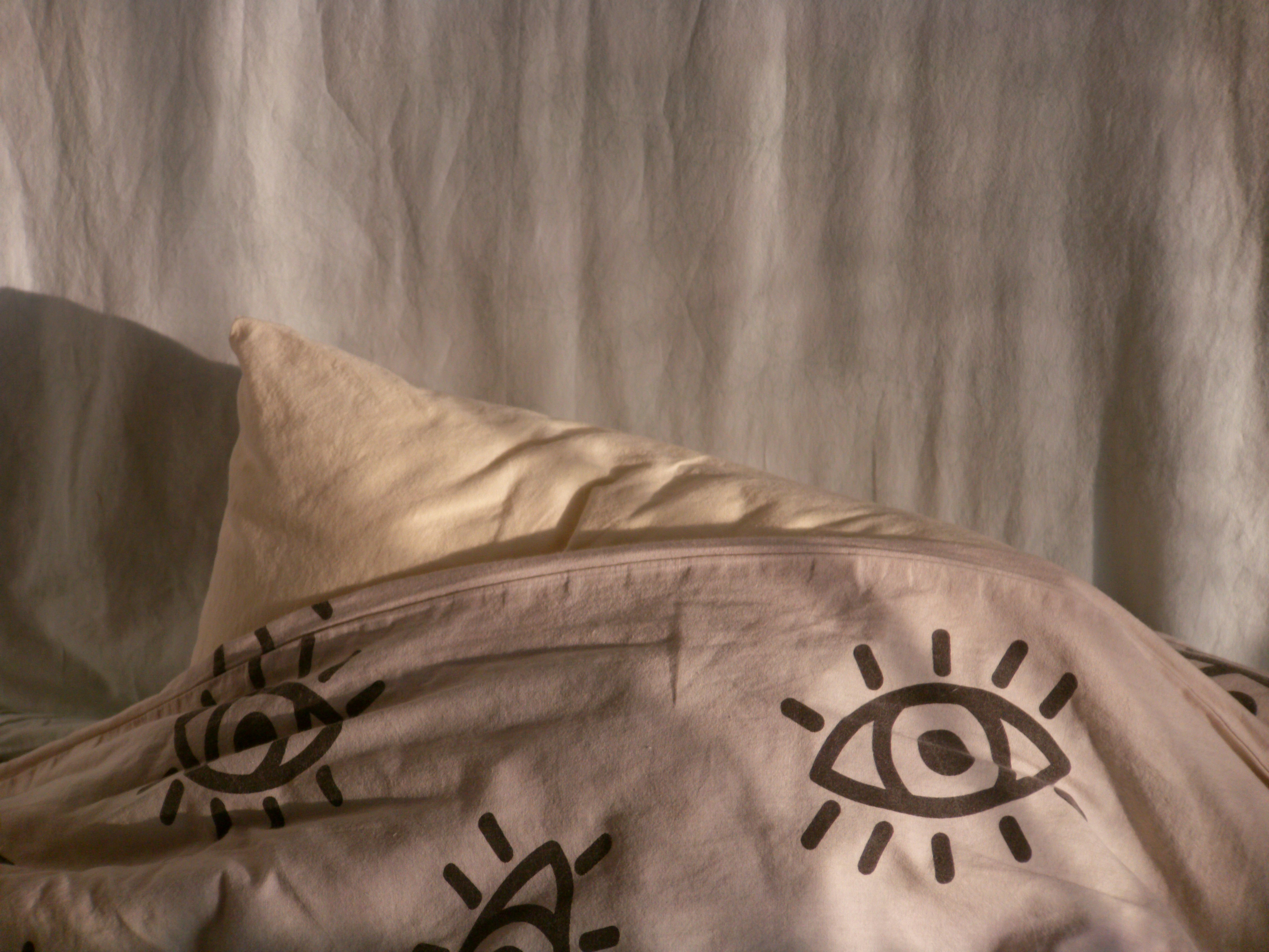 A pillow under a patterned sheet with eye designs