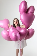 Young woman holding pink heart-shaped balloons