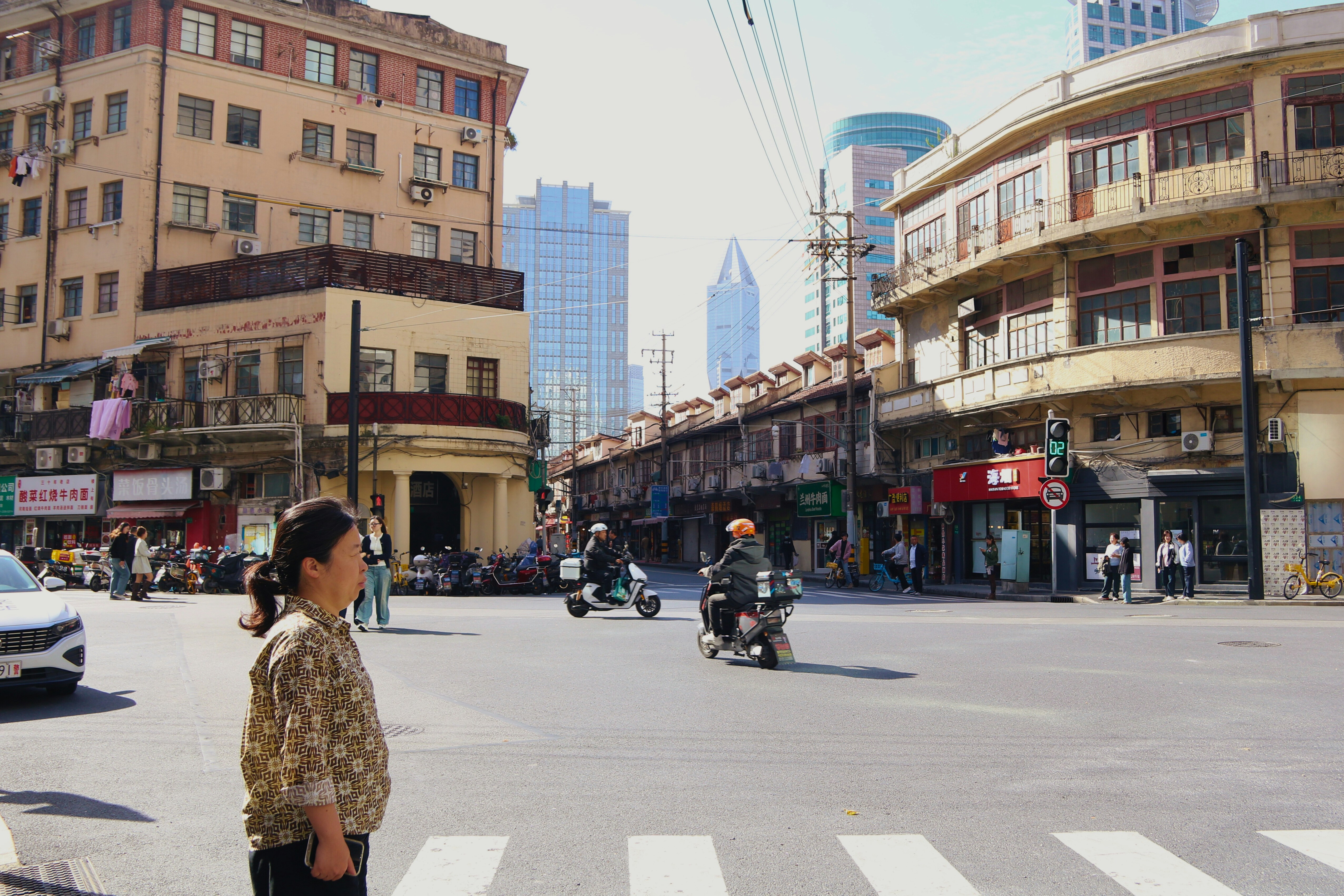 City street scene with buildings and people on scooters.