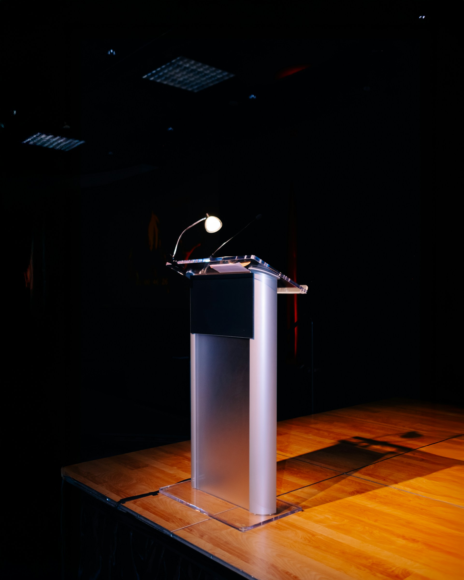 A modern podium with a microphone on a stage.