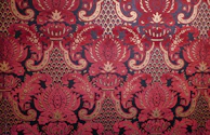Intricate red and gold paisley pattern on dark background.