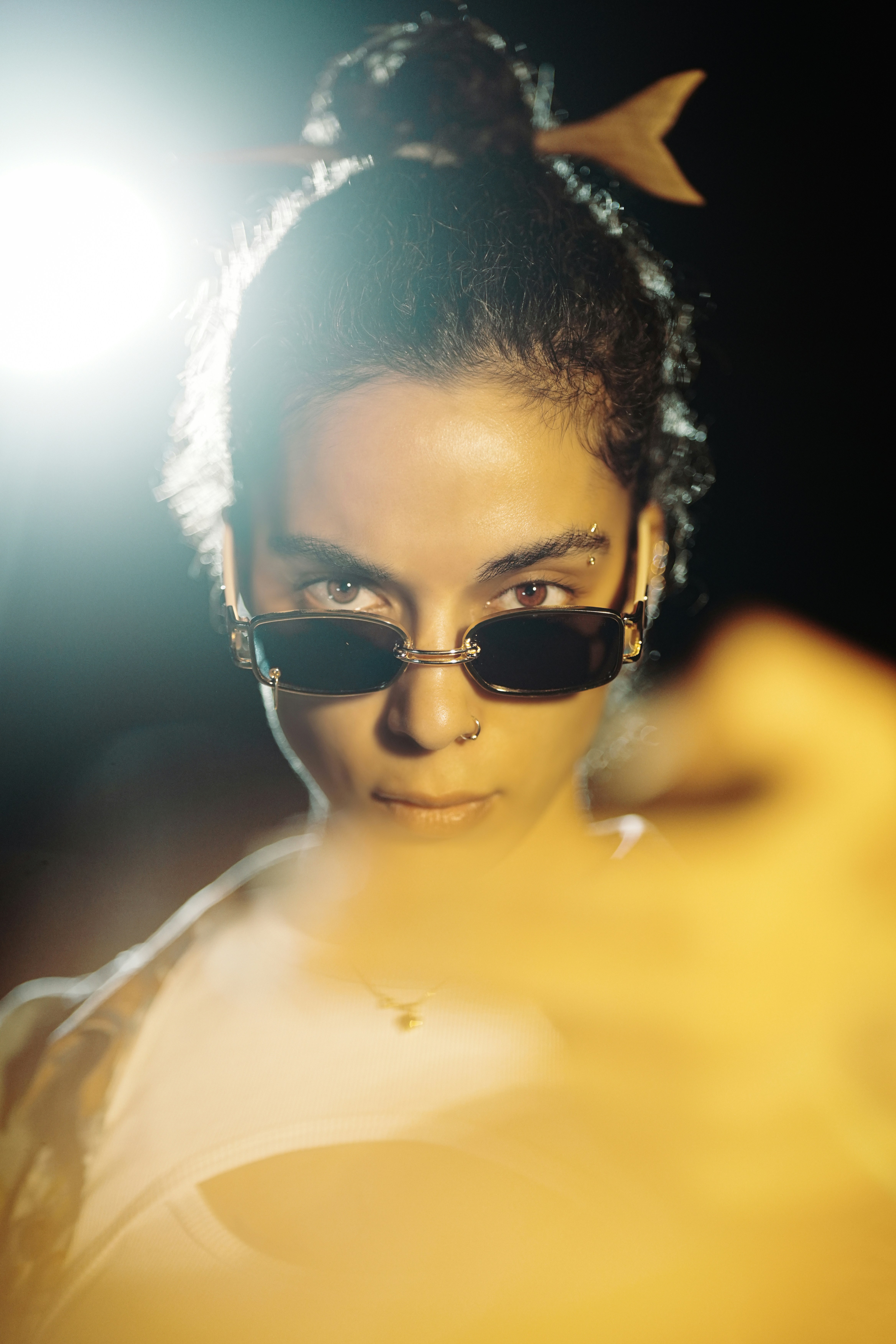 Woman with sunglasses and nose ring looks forward