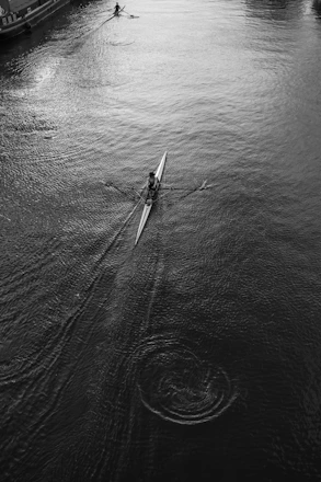 A lone rower glides across a dark, rippling river.