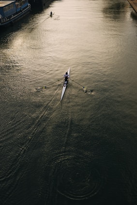 A single rower glides across a calm river.