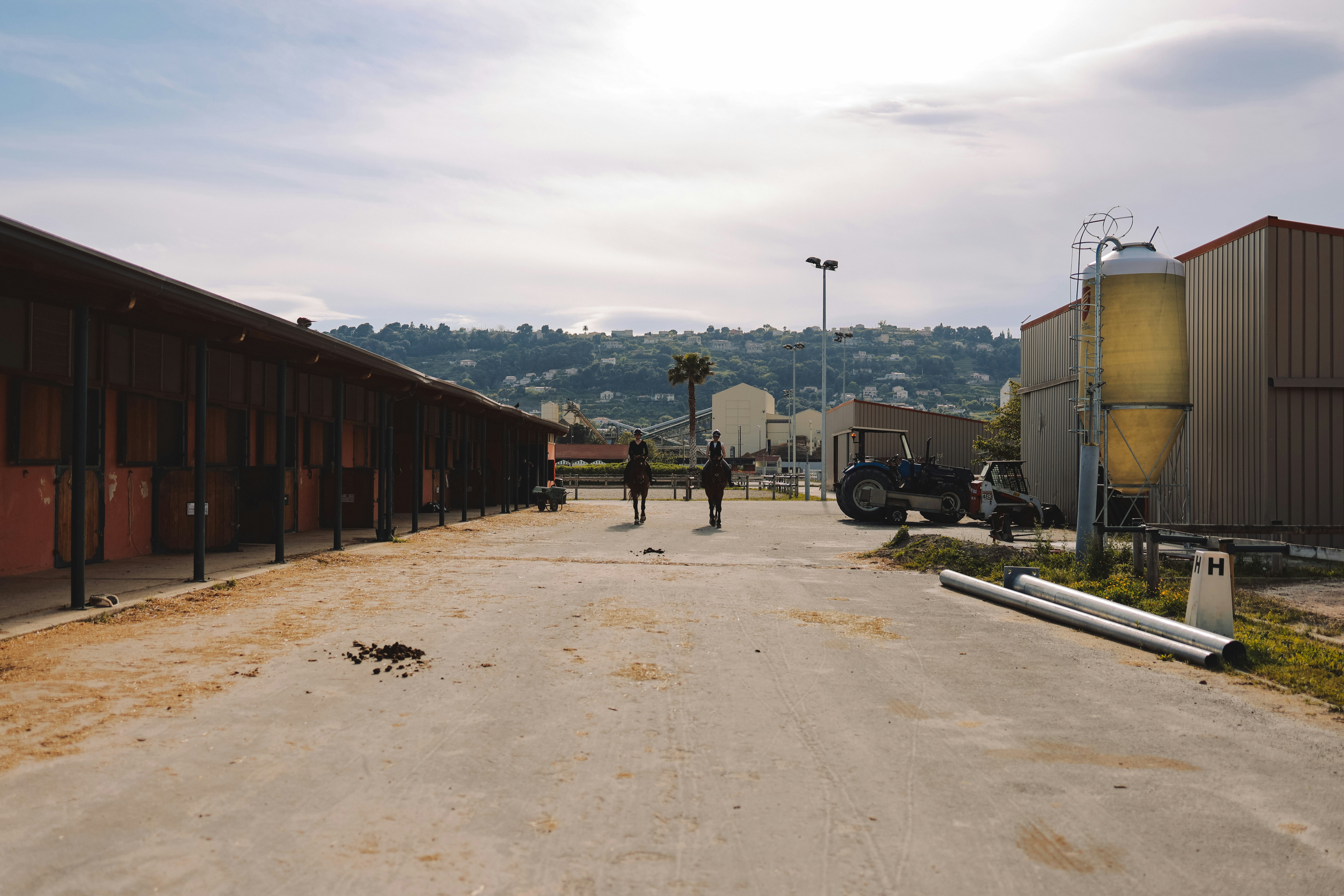 Pferdeställe und ein Traktor an einem sonnigen Tag.