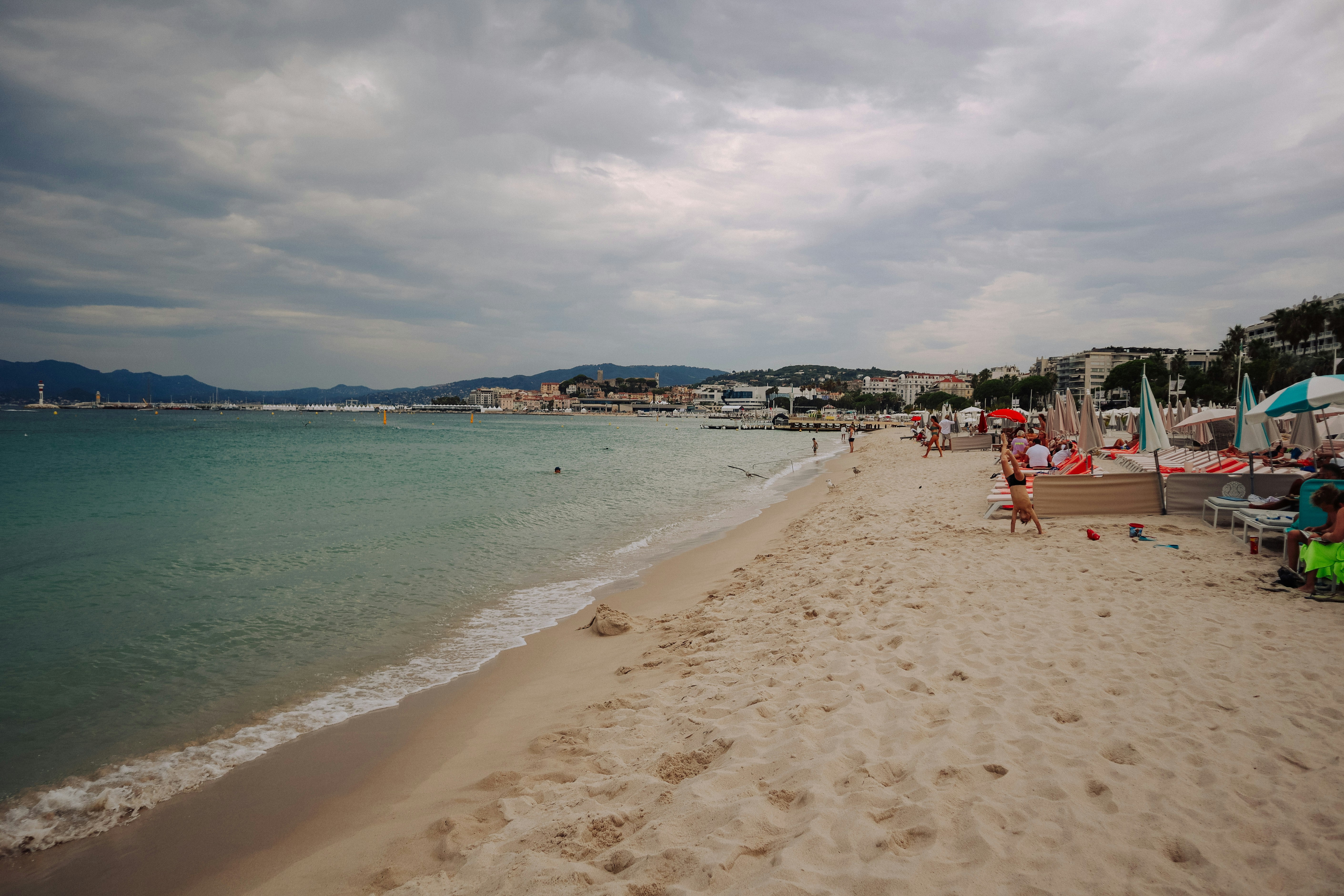 A sandy beach with lounge chairs and ocean waves.