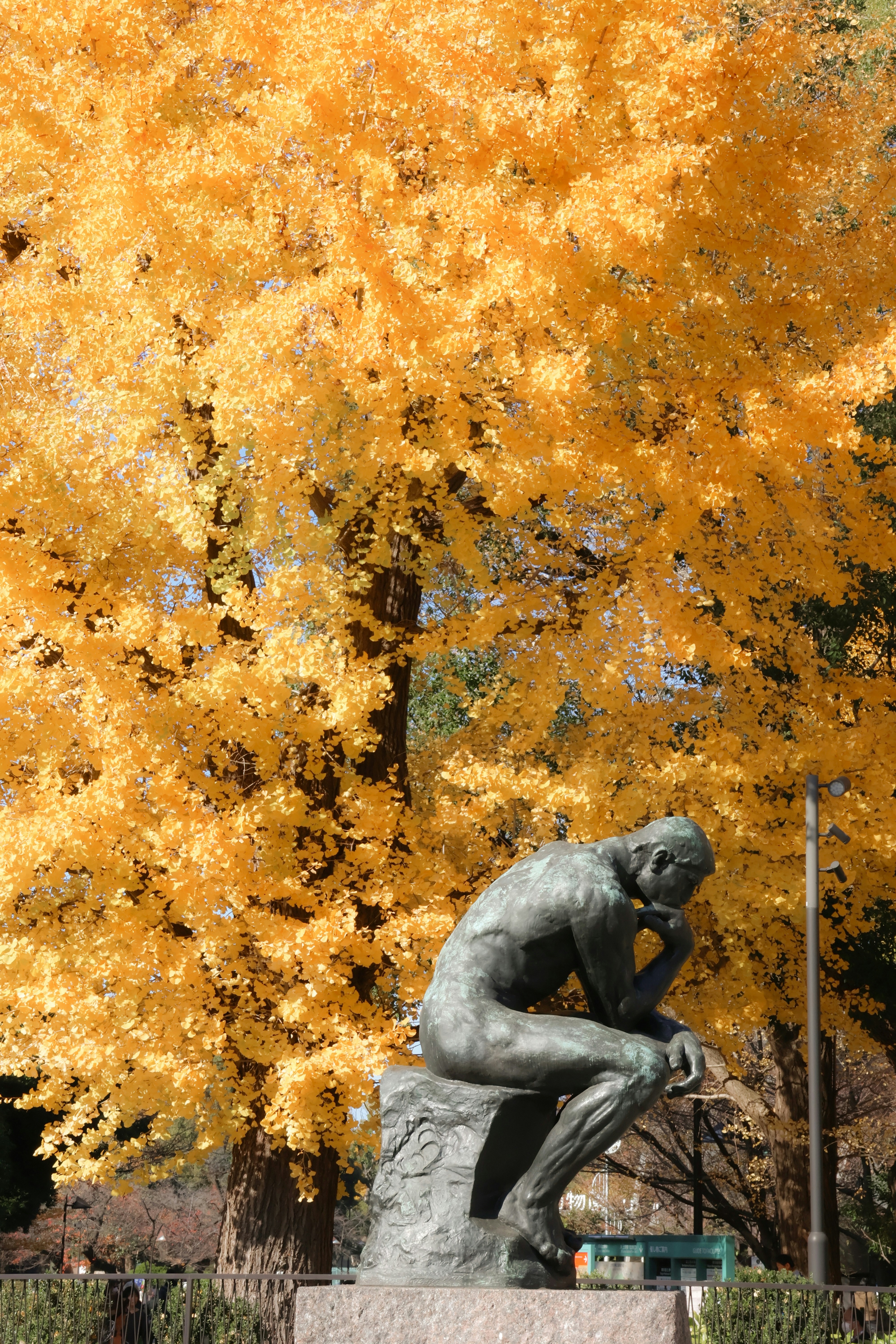 Statue of the thinker against golden autumn tree