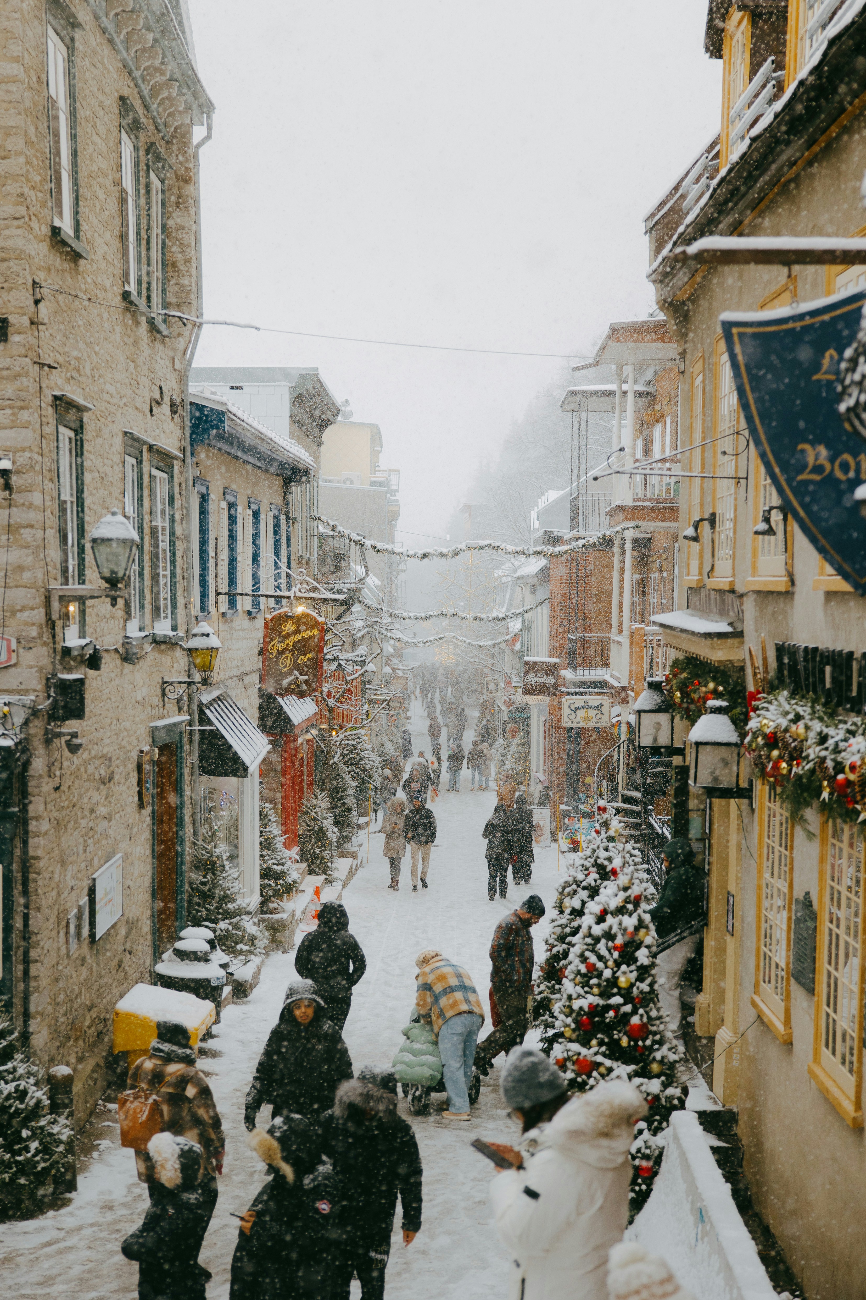 People walking on a snowy street in a historic town.