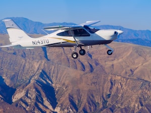 Small airplane flying over rugged mountains