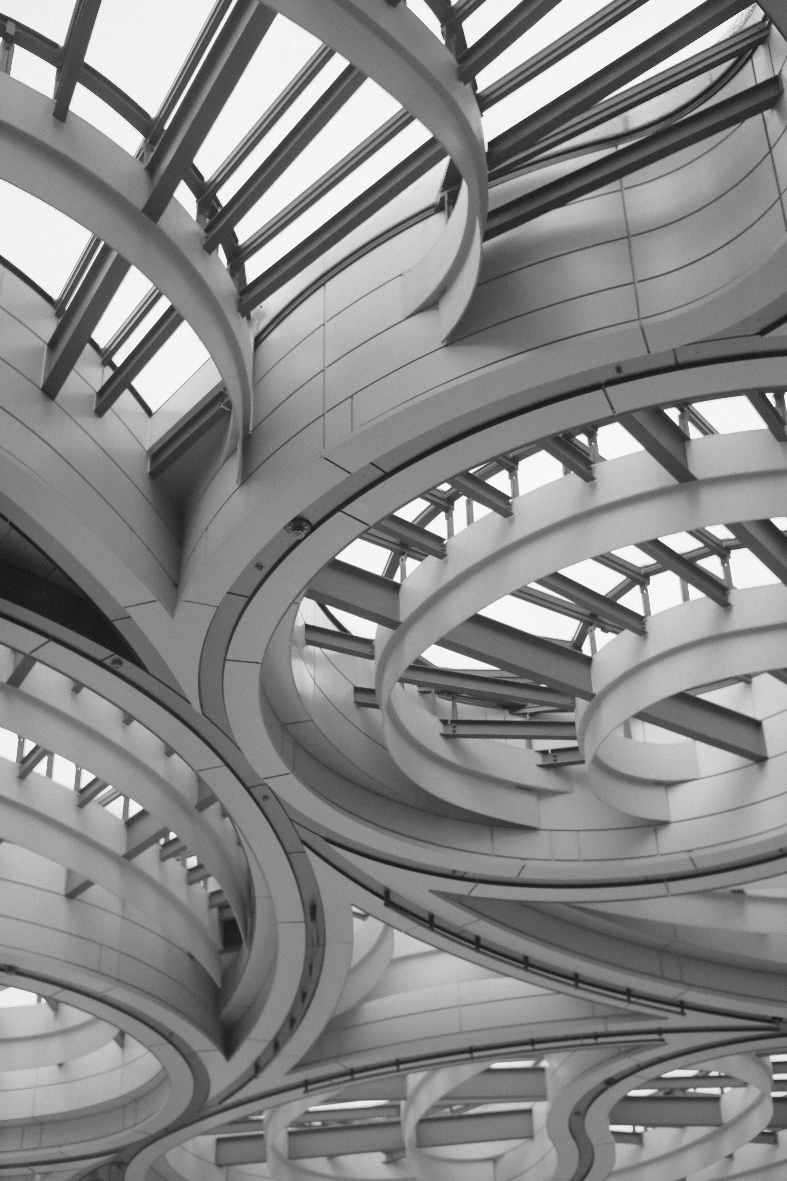 Curved white steel beams and glass panels forming a modern architectural ceiling structure