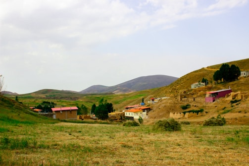 Rural village nestled in rolling hills under a cloudy sky.