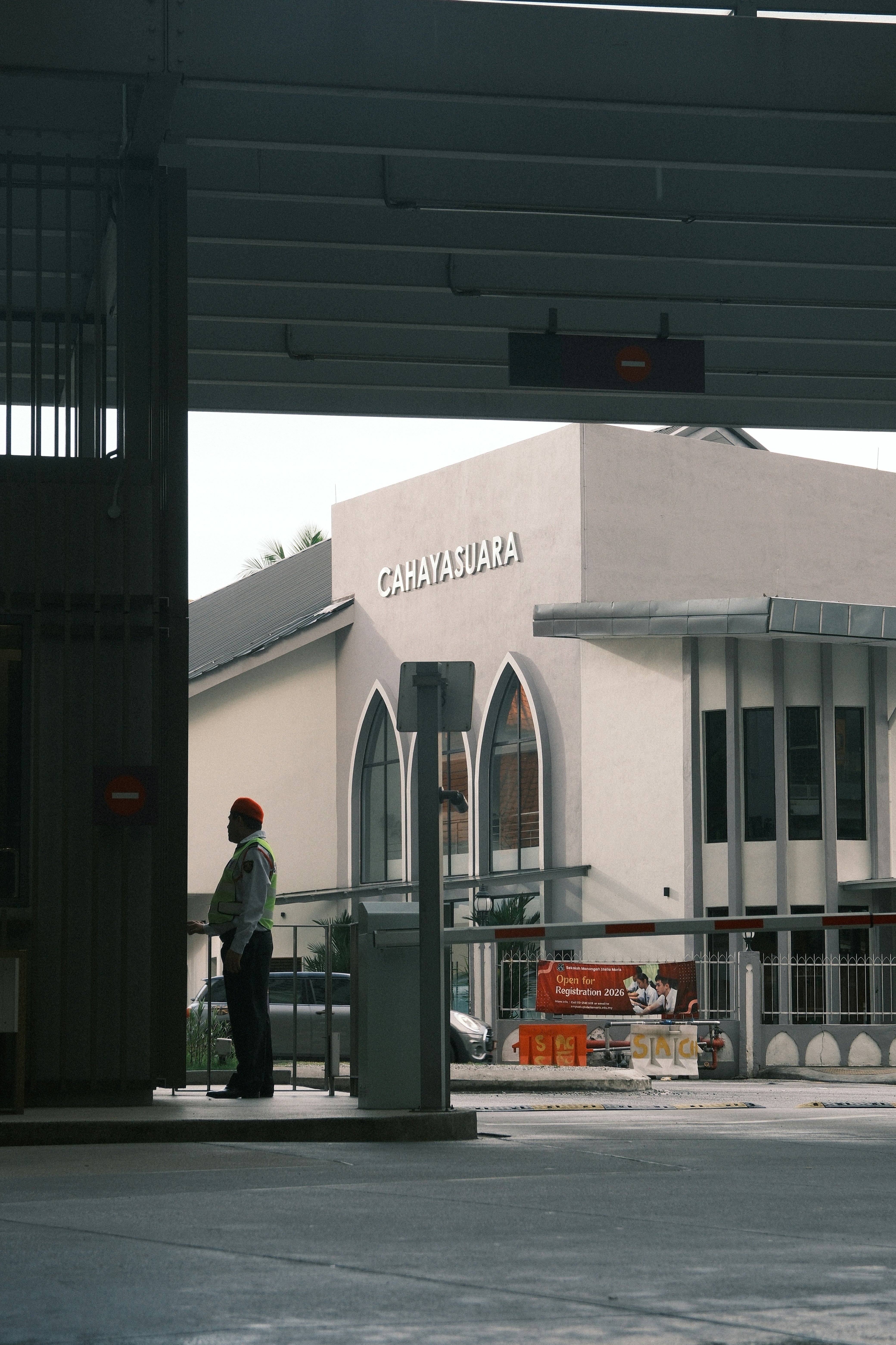 Security guard stands near building entrance with barrier gates.