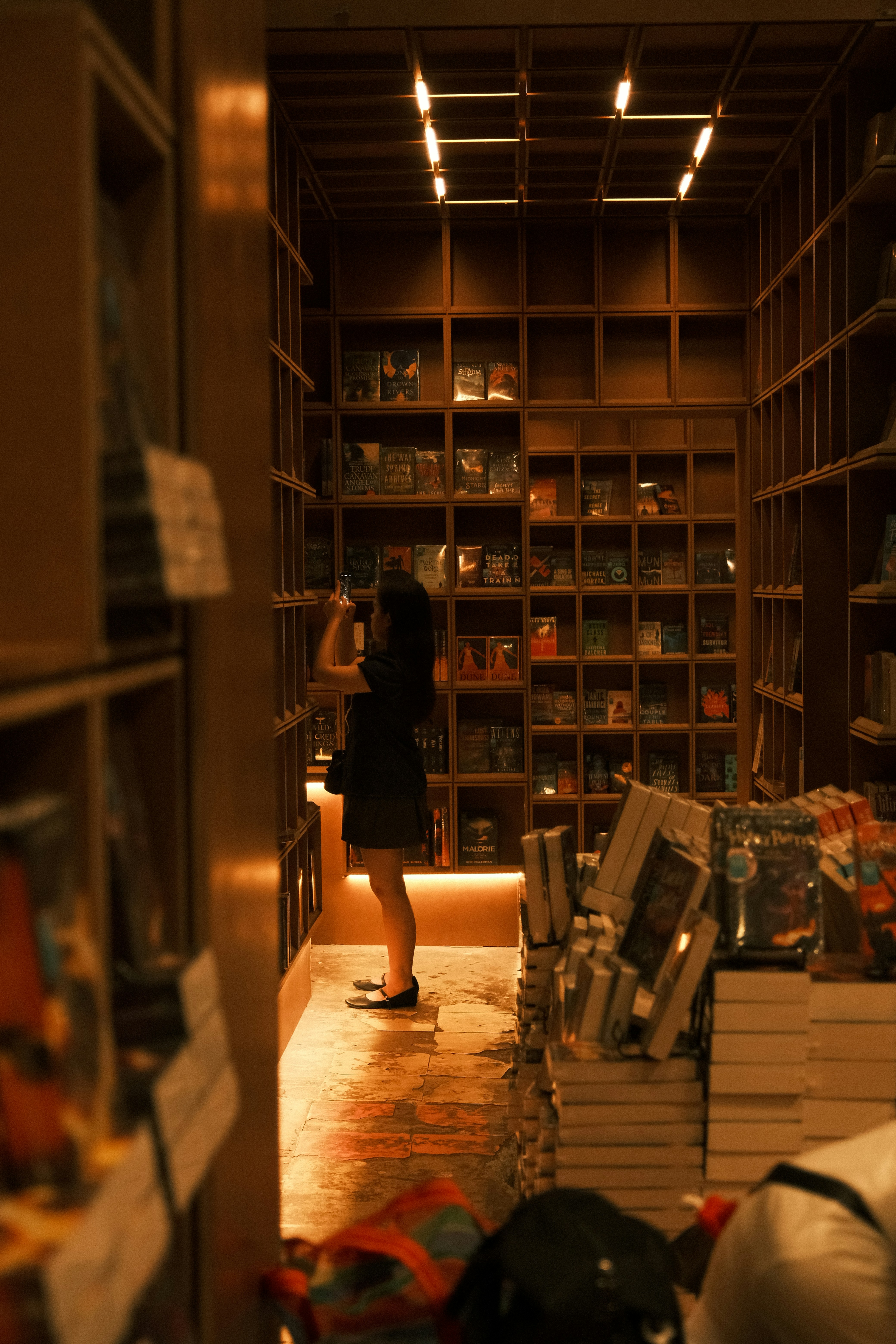 Femme qui parcourt les étagères d’une librairie chaleureuse