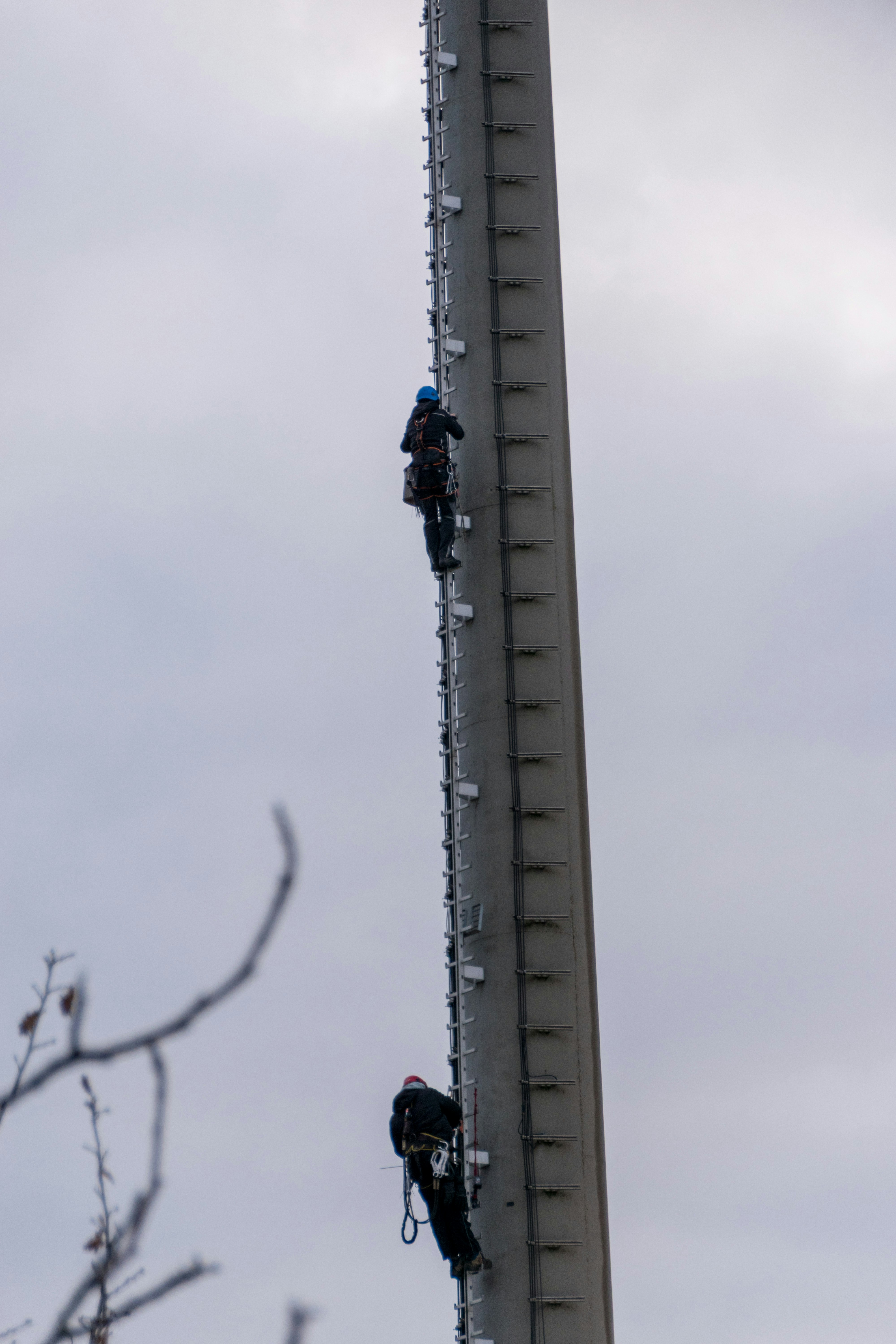 Two workers climbing a tall communication tower