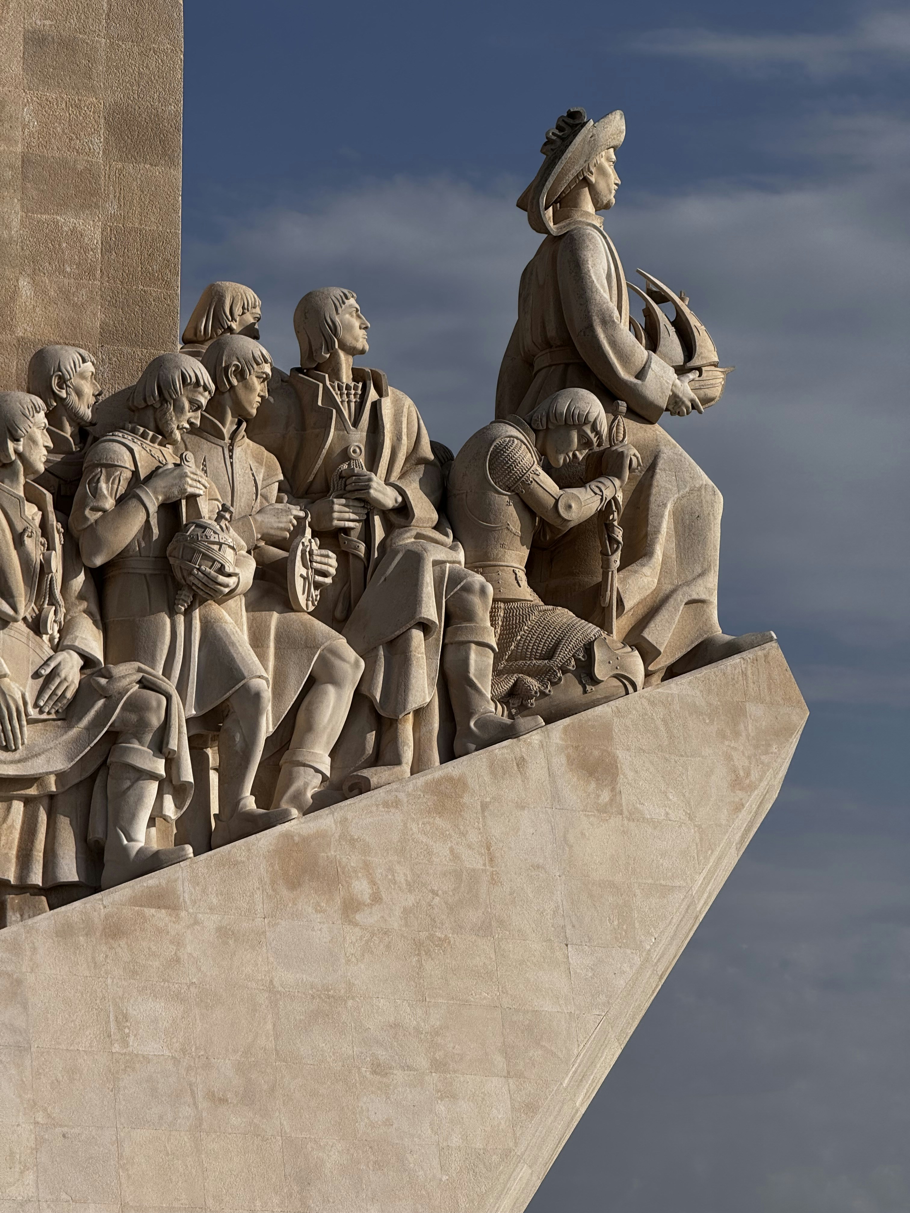 Monumental stone sculpture of explorers against blue sky
