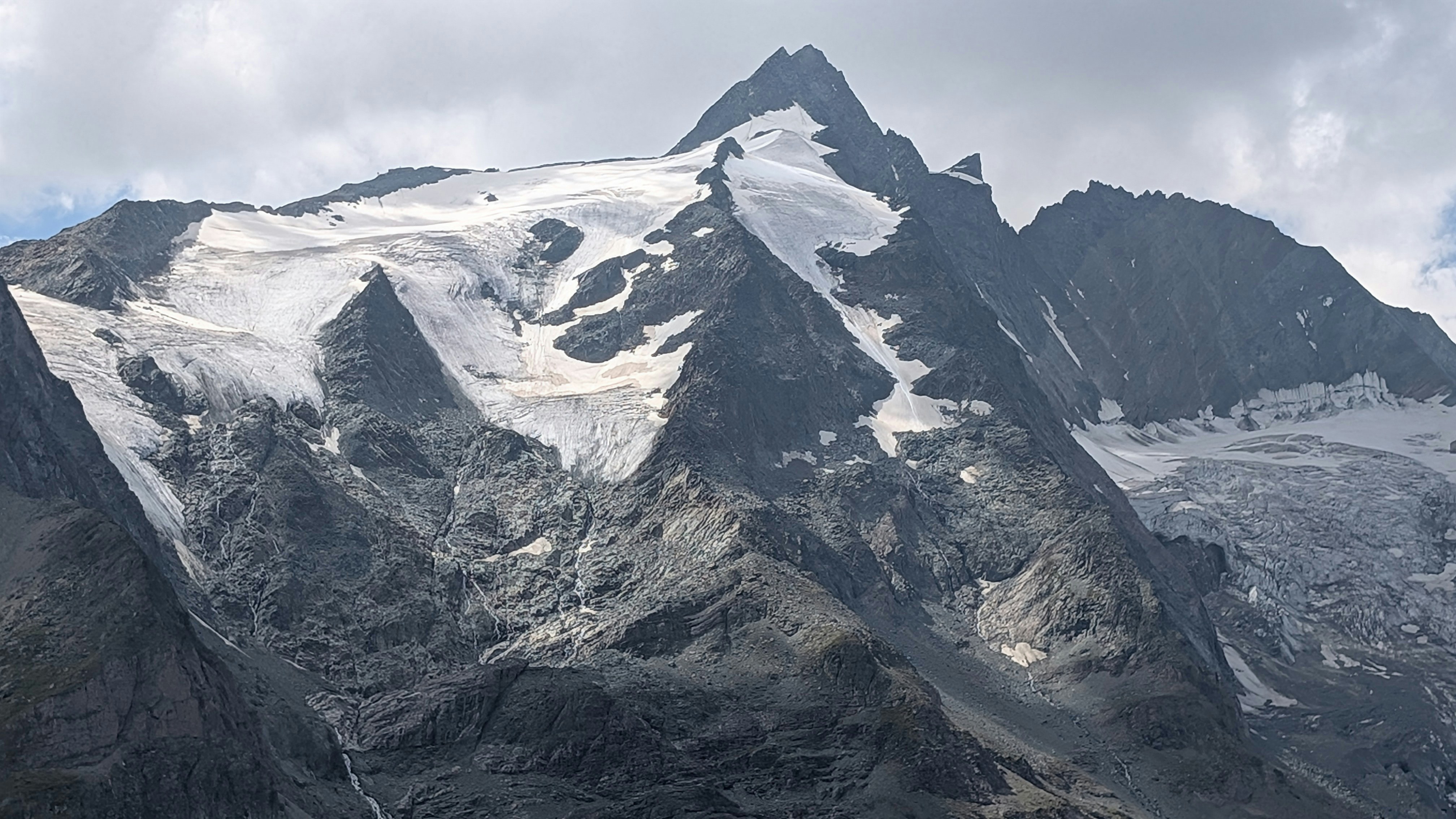 Snow-capped mountain peaks under a cloudy sky