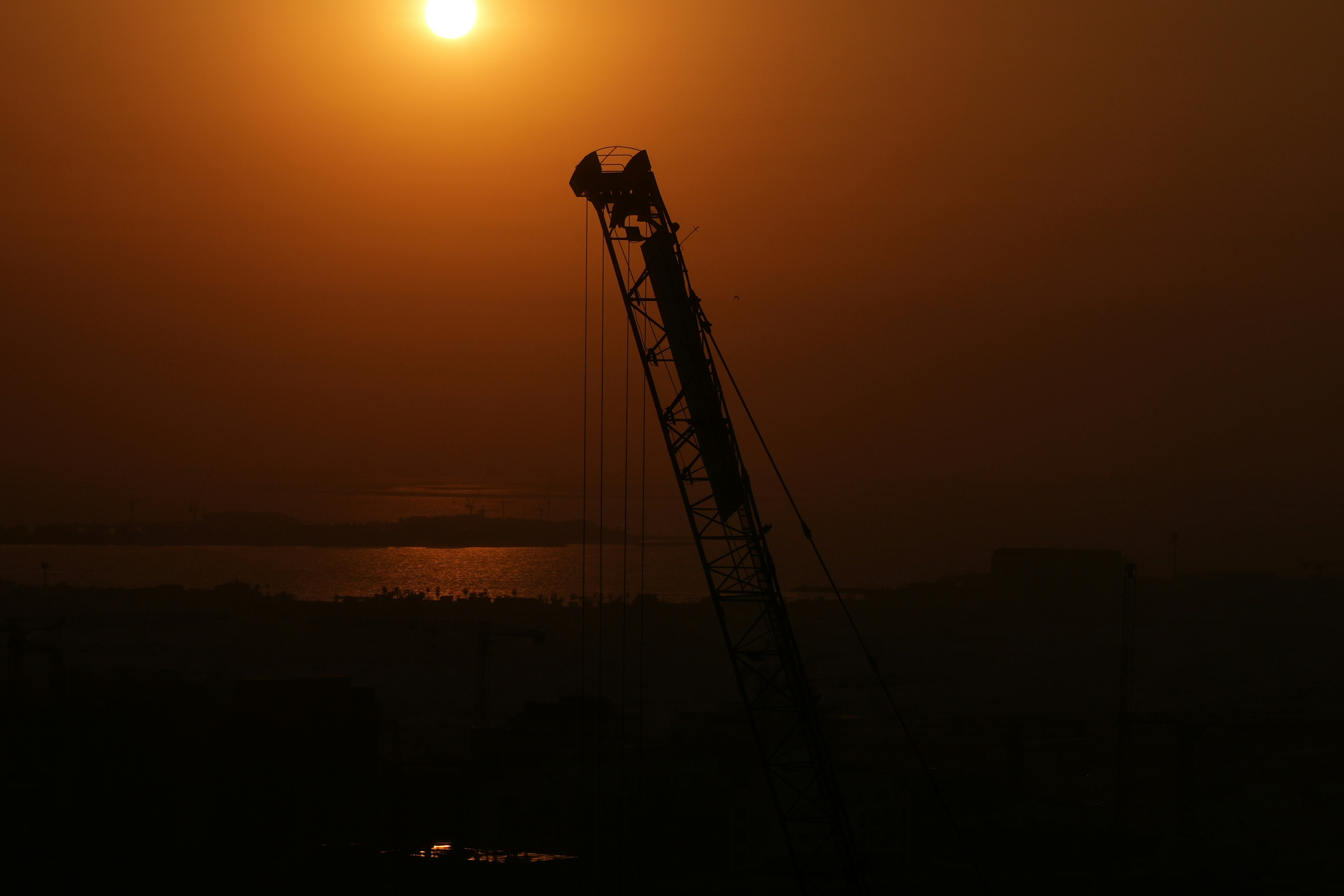 Silhouette of crane against sunset over water