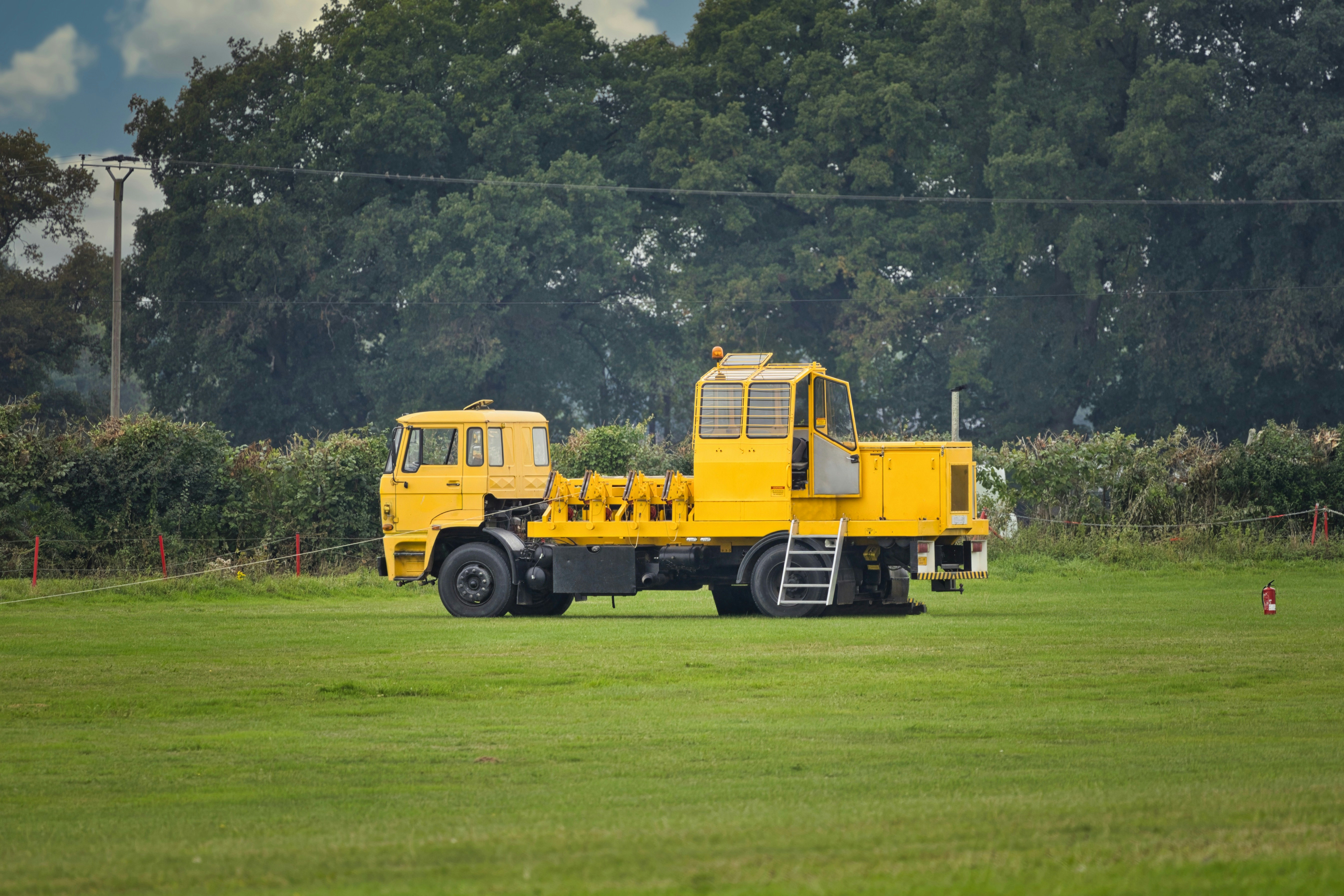 A yellow utility vehicle parked on a grassy field.