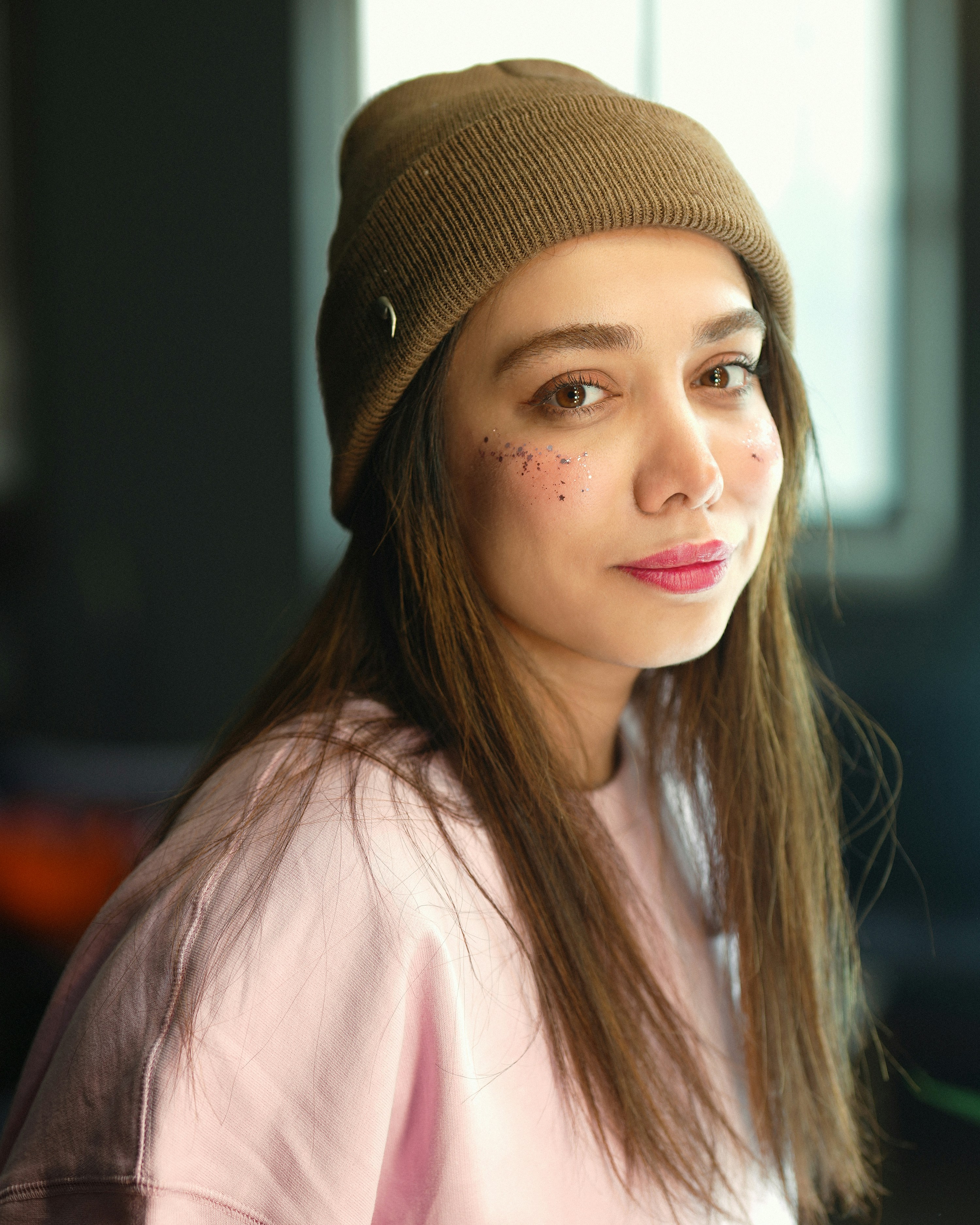 Young woman wearing a brown beanie and pink sweatshirt.