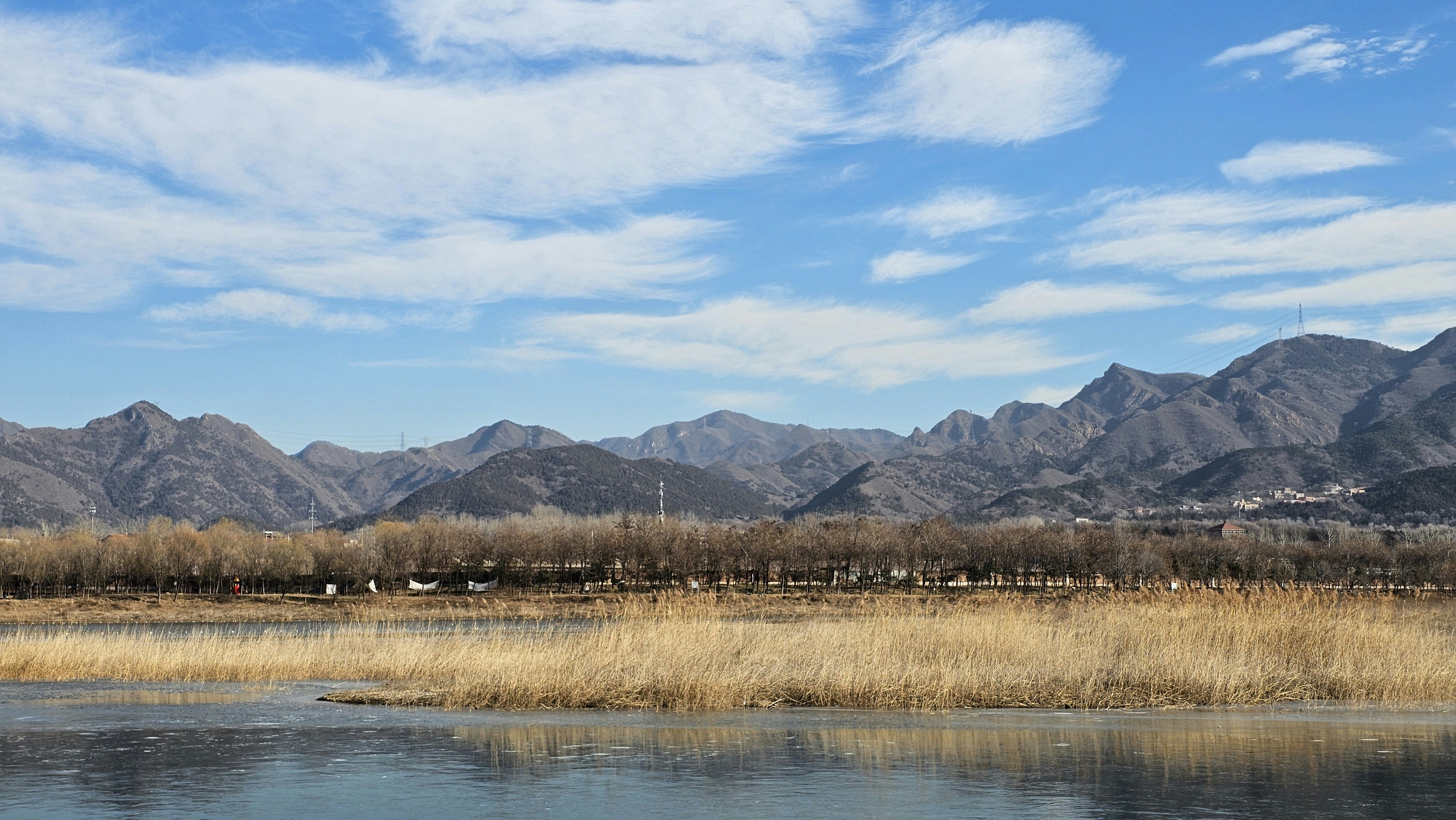 Dry grass field with mountains and blue sky