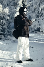 Person in winter gear standing in snowy forest