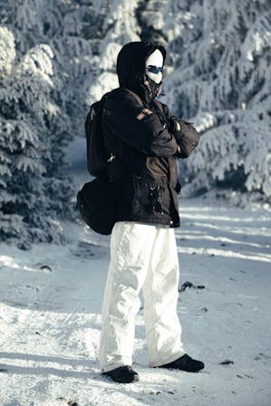 Person in winter gear standing in snowy forest