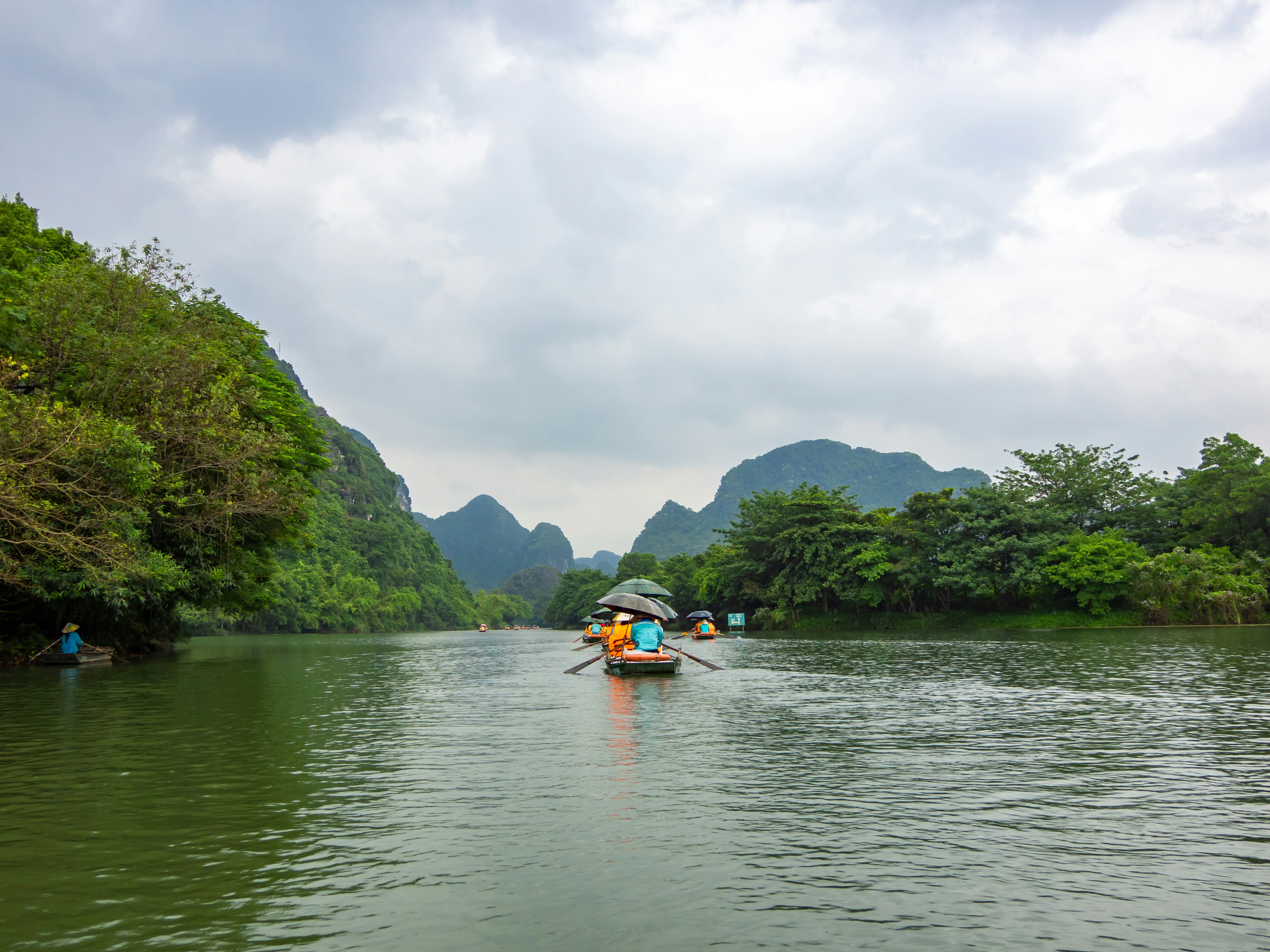 Boats on a river surrounded by lush green mountains.