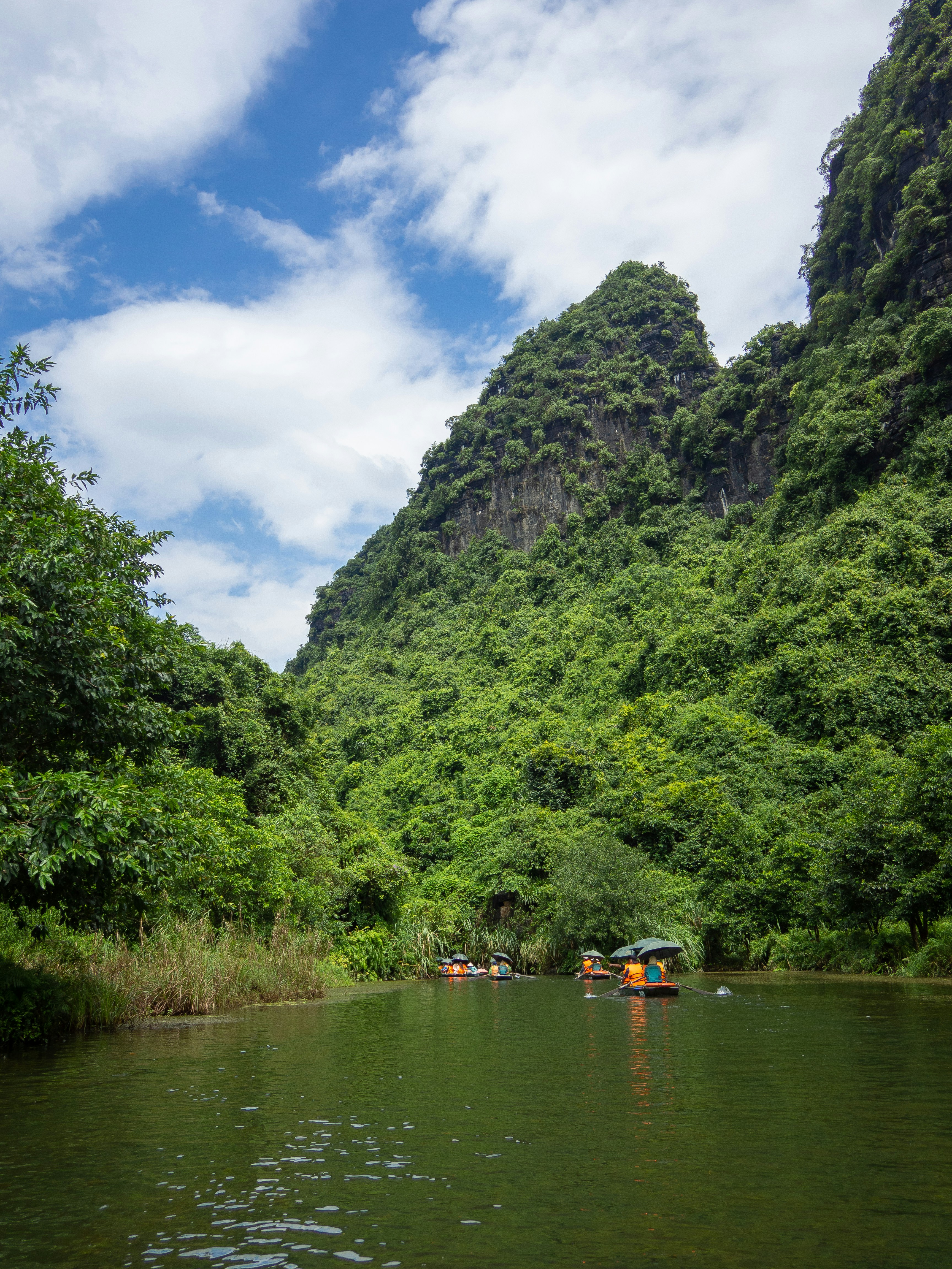 Boats on a river surrounded by lush green mountains.