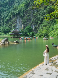 Woman by lake with boats and pagoda