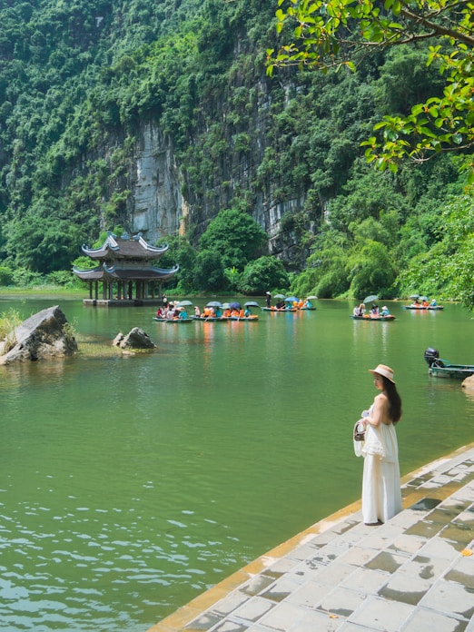 Woman by lake with boats and pagoda