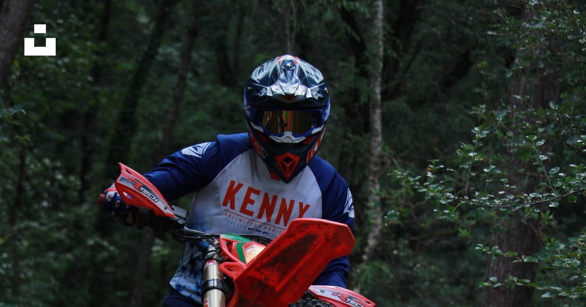 Pilote de motocross effectuant un wheeling sur un sentier forestier ...