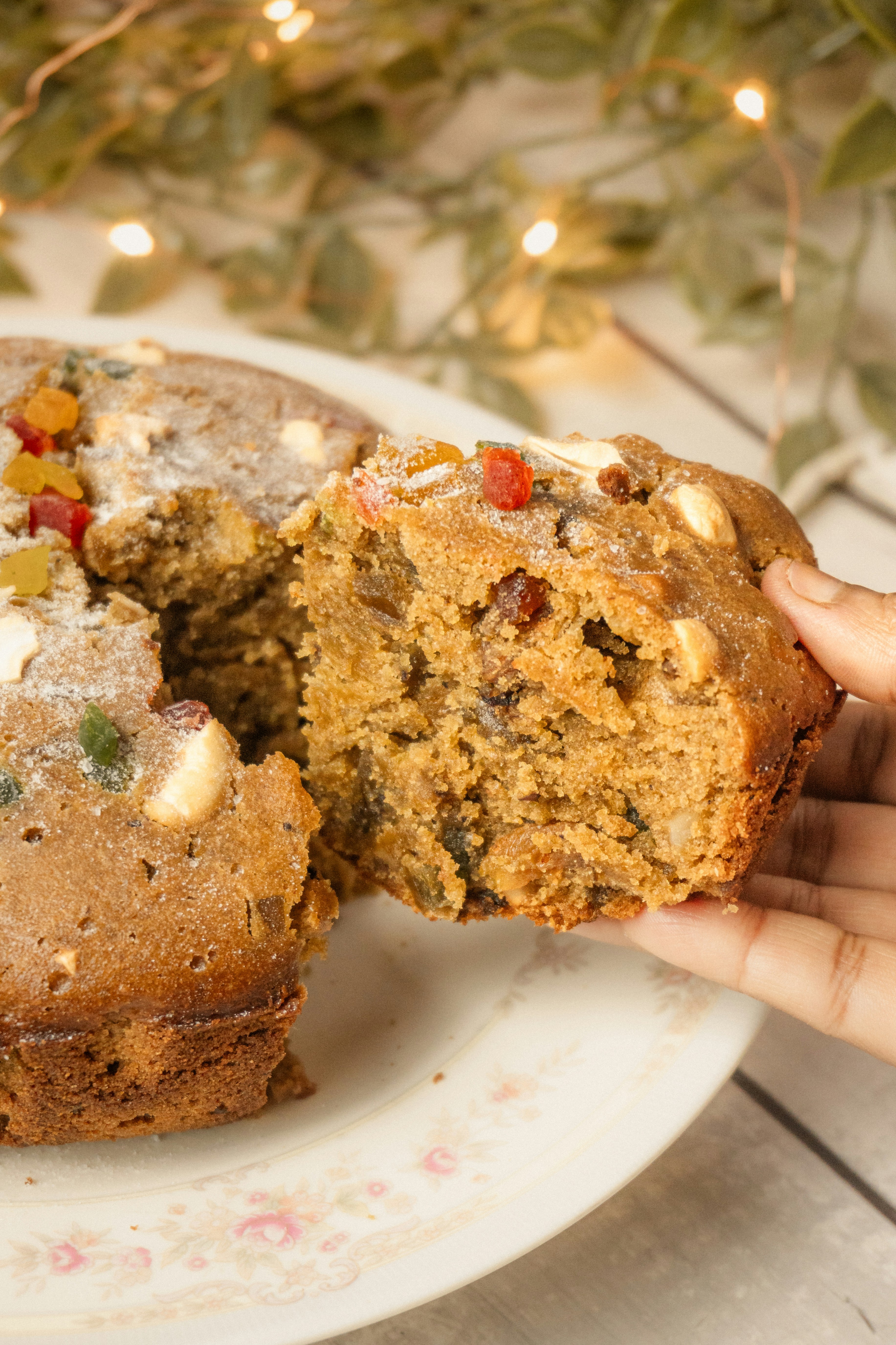 Hand holding a slice of fruitcake with nuts cake