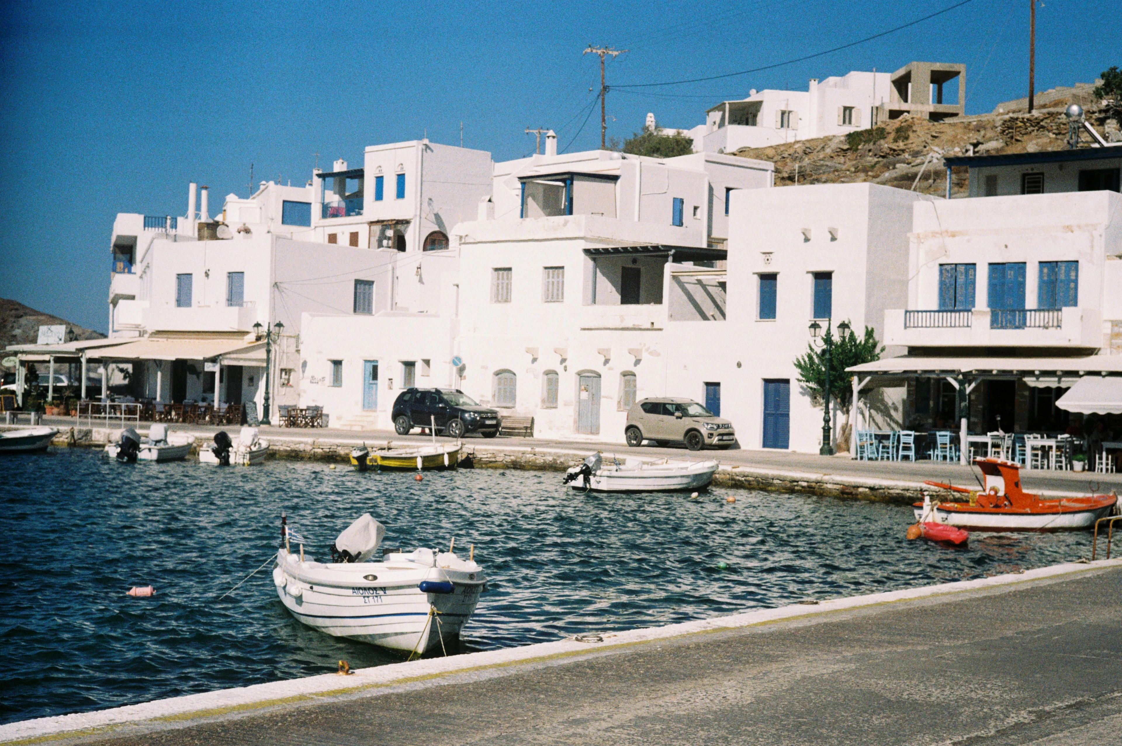 A calm harbour front with small boats and whitewashed houses, Tinos, Greece
