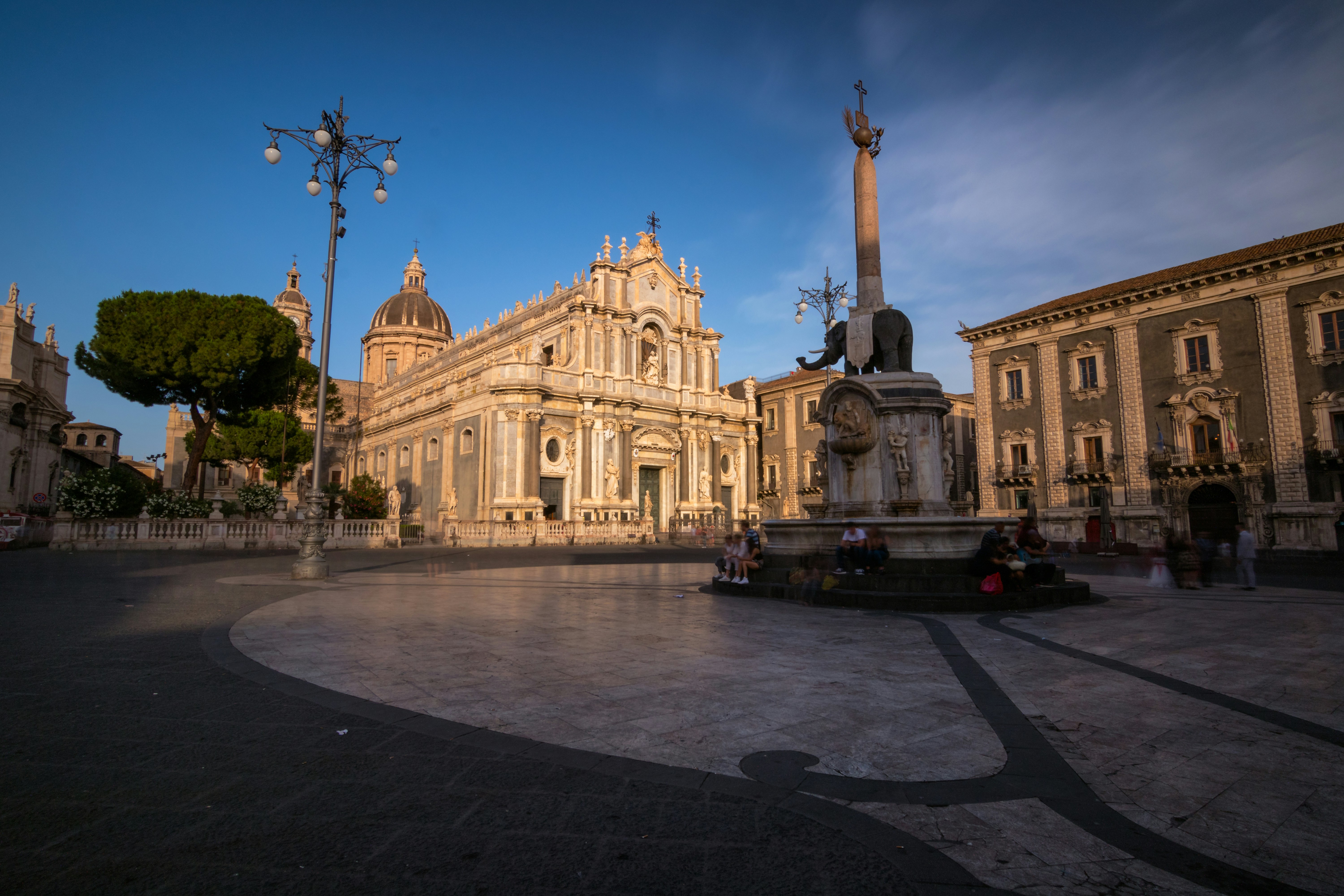 Baroque cathedral and monument in a sunny piazza.