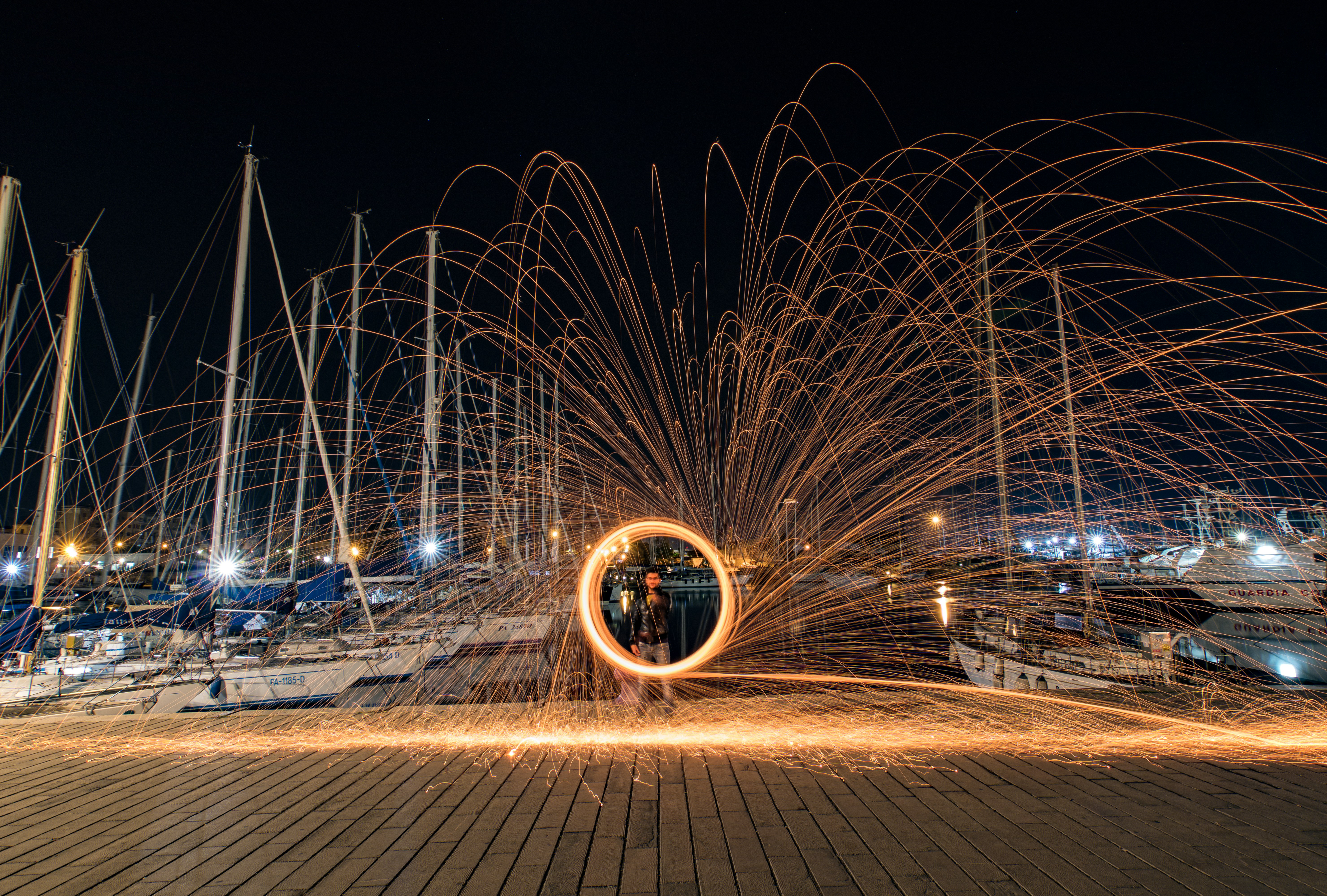 Sparkler art creates a fiery circle at night marina.