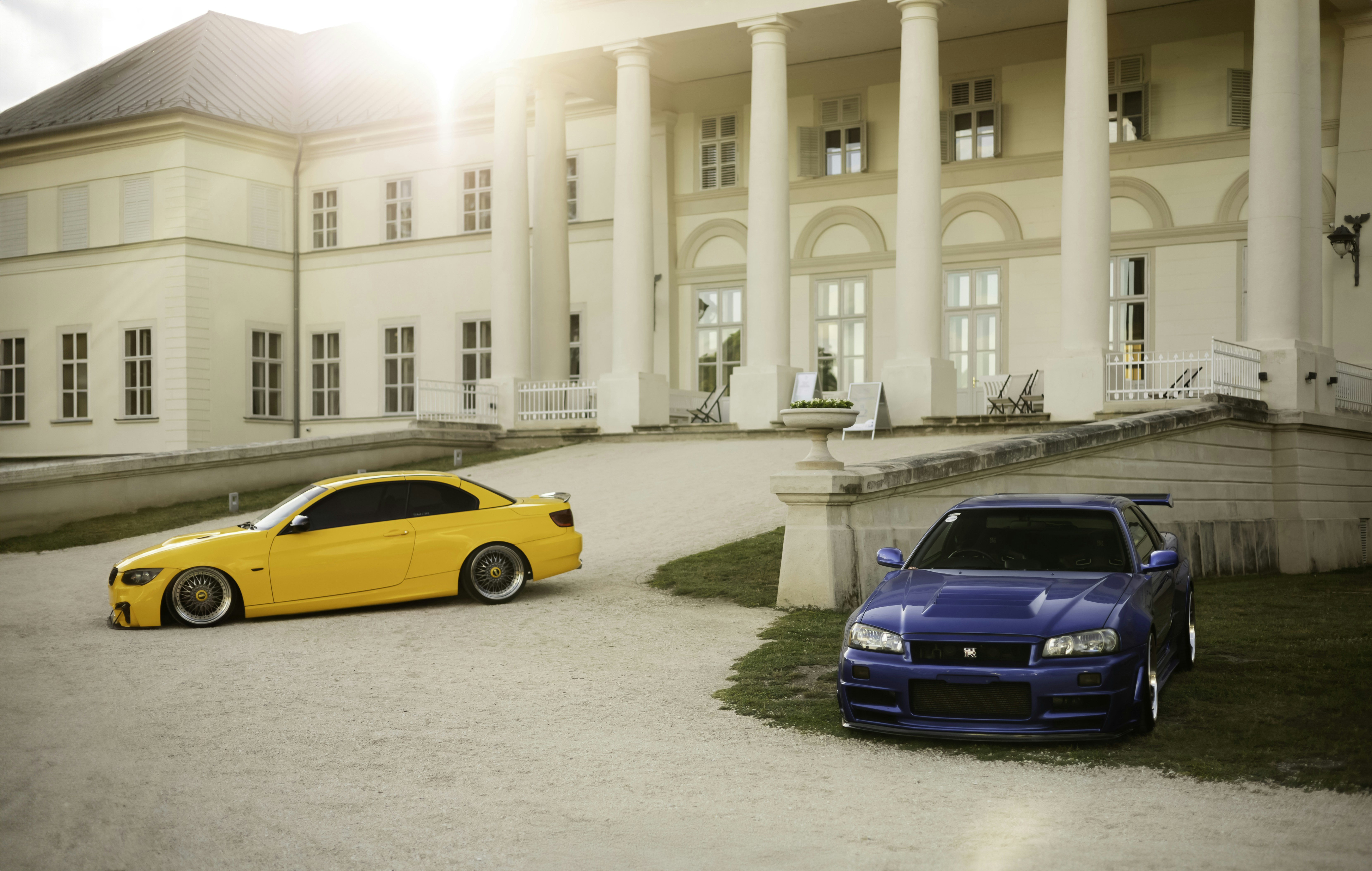 Two sports cars parked in front of a grand building.