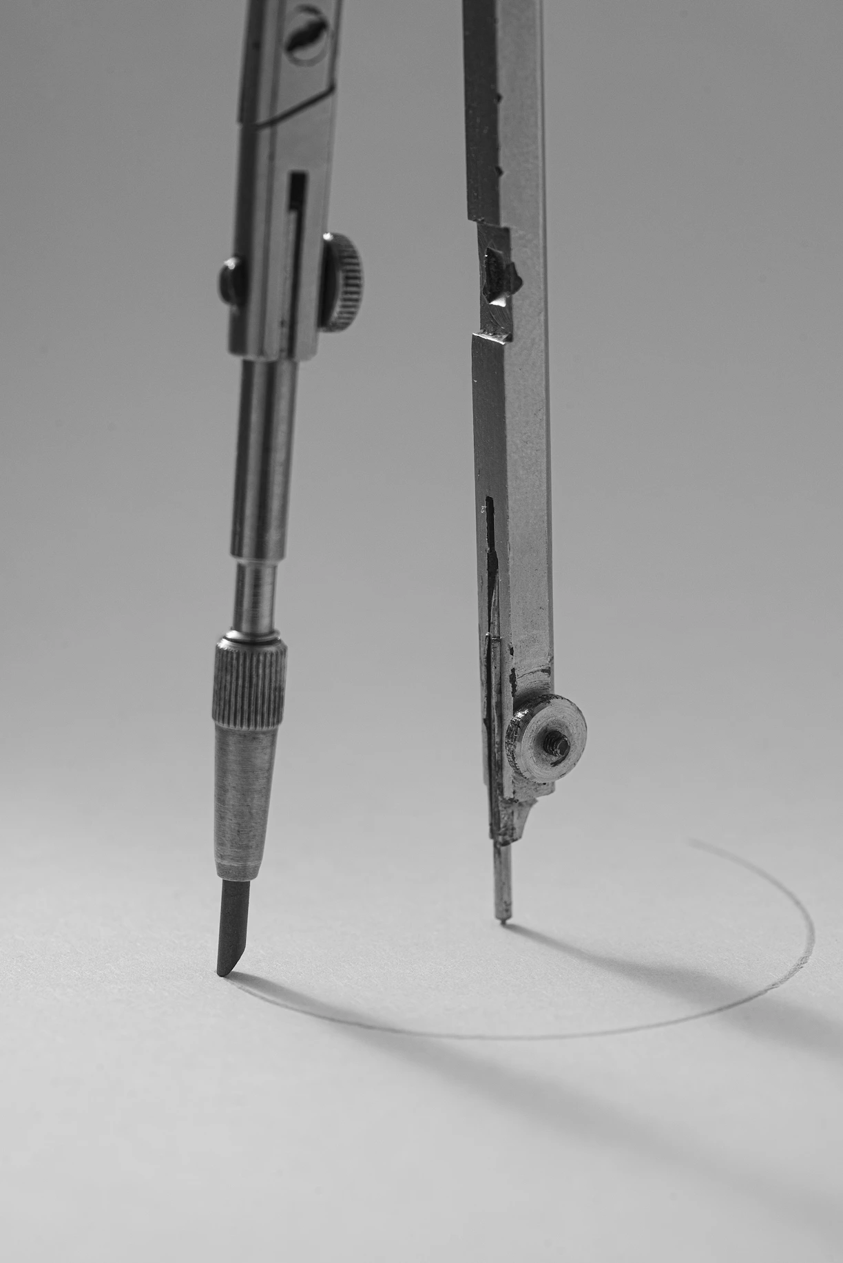 A drafting compass drawing a circle on paper.